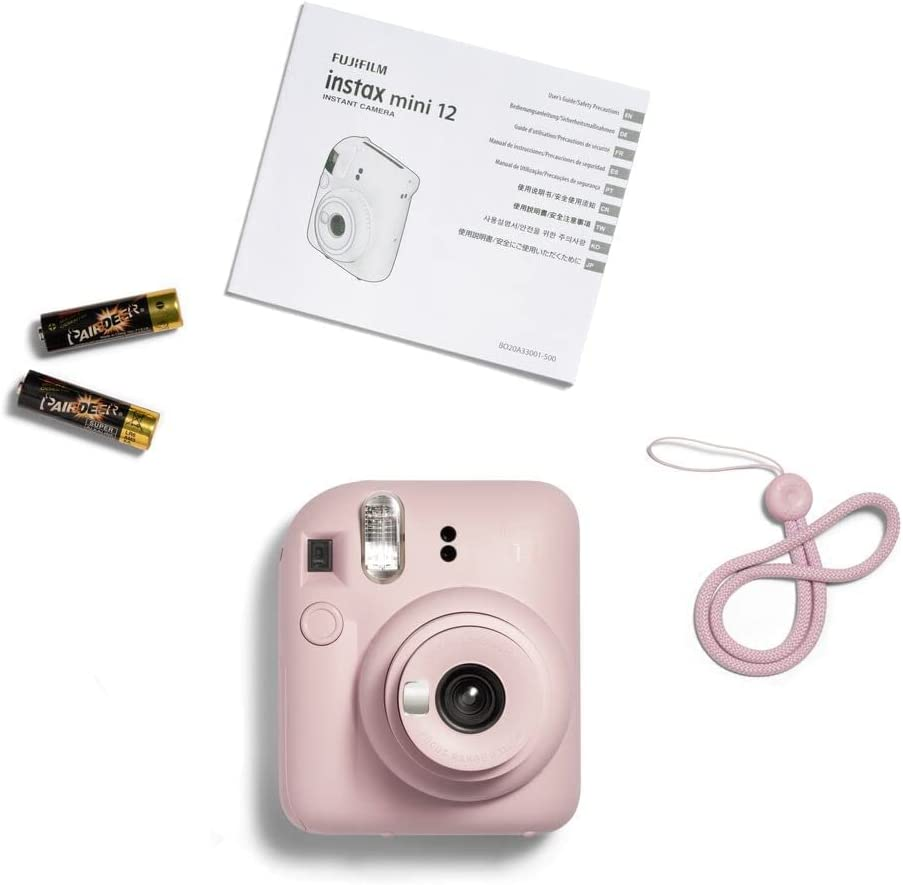 Cámara Fujifilm Instax Mini 12 rosa con accesorios: pilas, correa y manual de instrucciones.