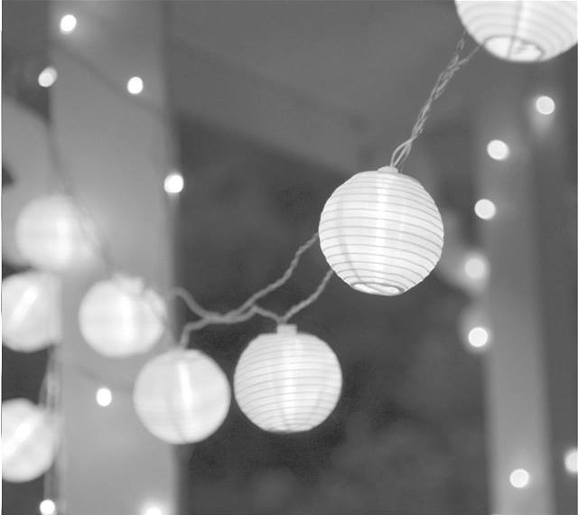 Guirlande de lanternes en papier blanc suspendues à un plafond blanc.
