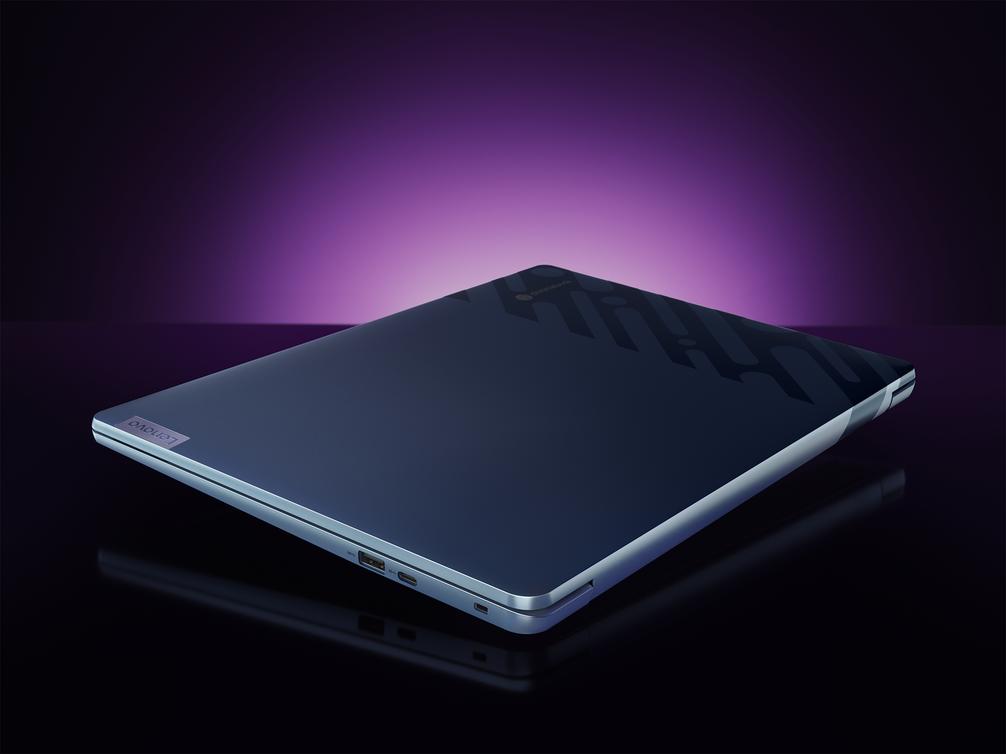 Geschlossener marineblauer Lenovo-Laptop mit einer verspiegelten Oberfläche, die einen violett beleuchteten Hintergrund reflektiert.
