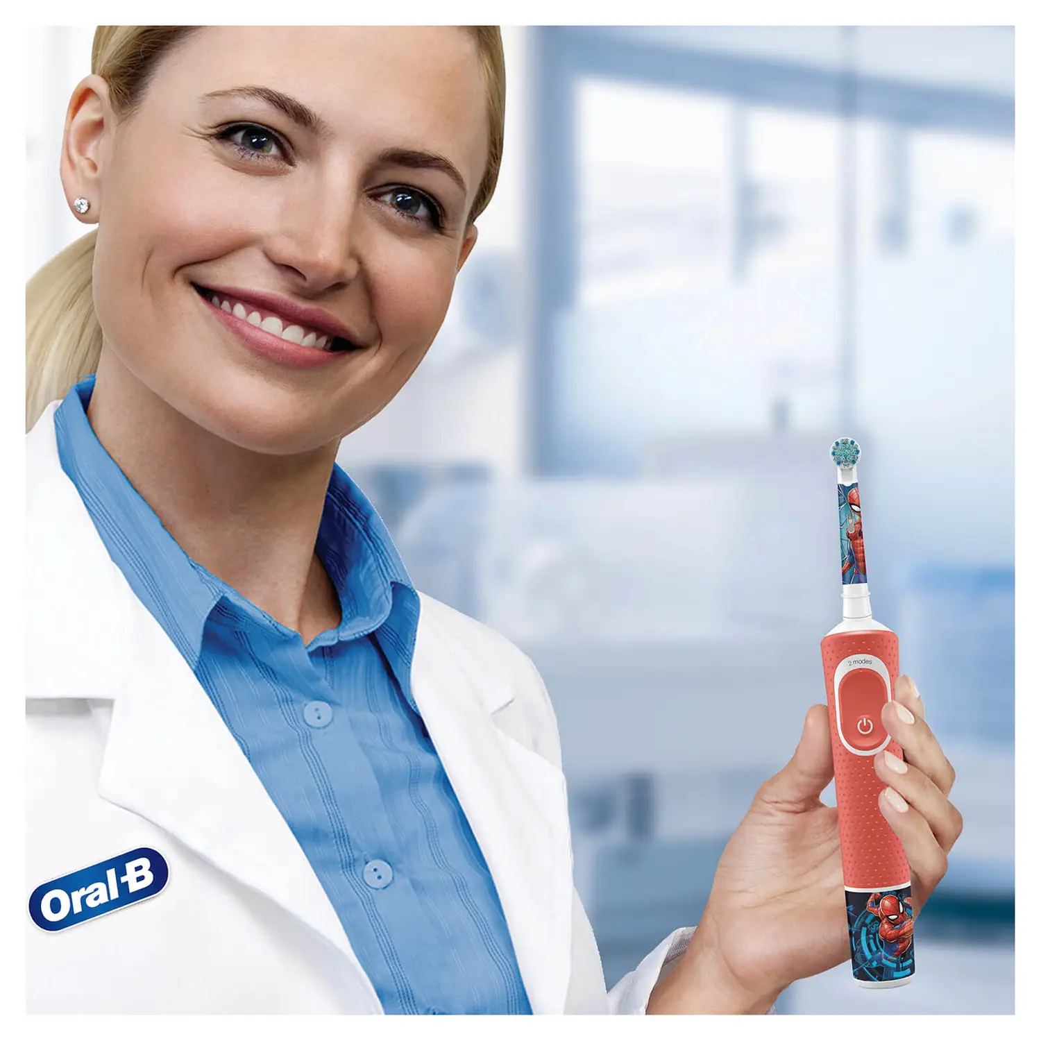 Une femme en blouse blanche tient une brosse à dents Spider-Man rouge et bleue.