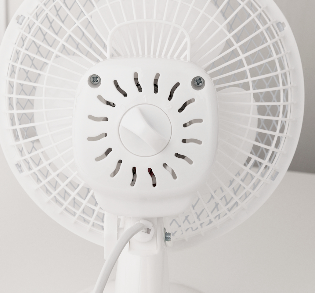 Rückansicht eines weißen elektrischen Ventilators mit Griff und Gitter.