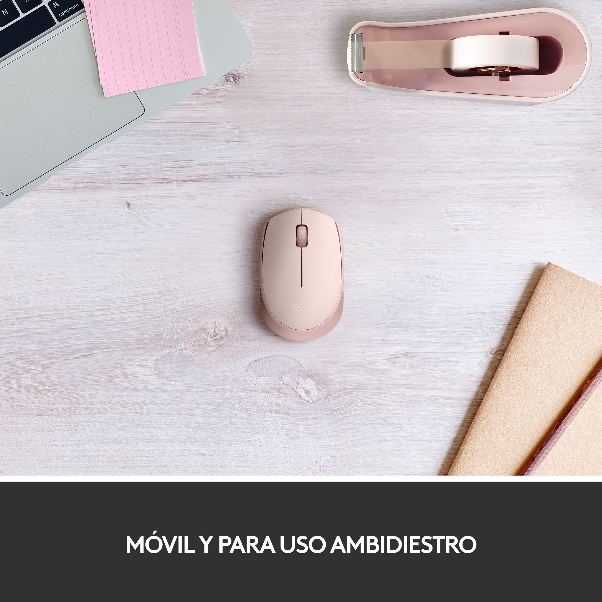 Ratón de ordenador rosa, bloc de notas y dispensador de cinta adhesiva en escritorio de madera.