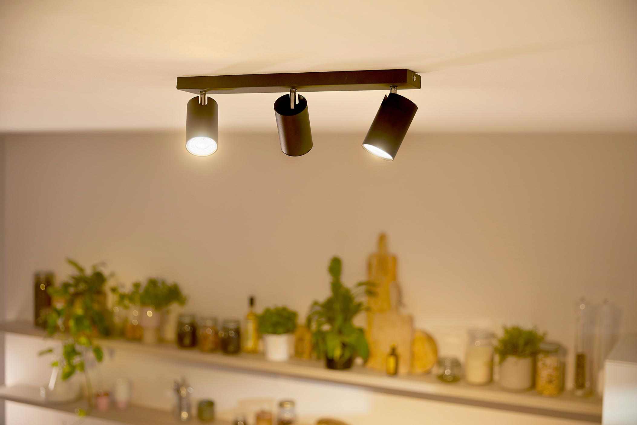Drei schwarze Strahler auf einer schwarzen Stange, mit hellem Licht von jedem.