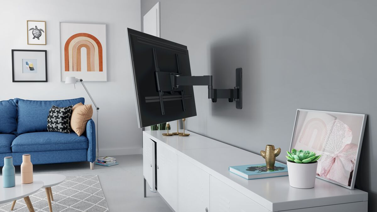 Un televisor montado en una pared, con un armario, un sofá y decoración en el fondo.