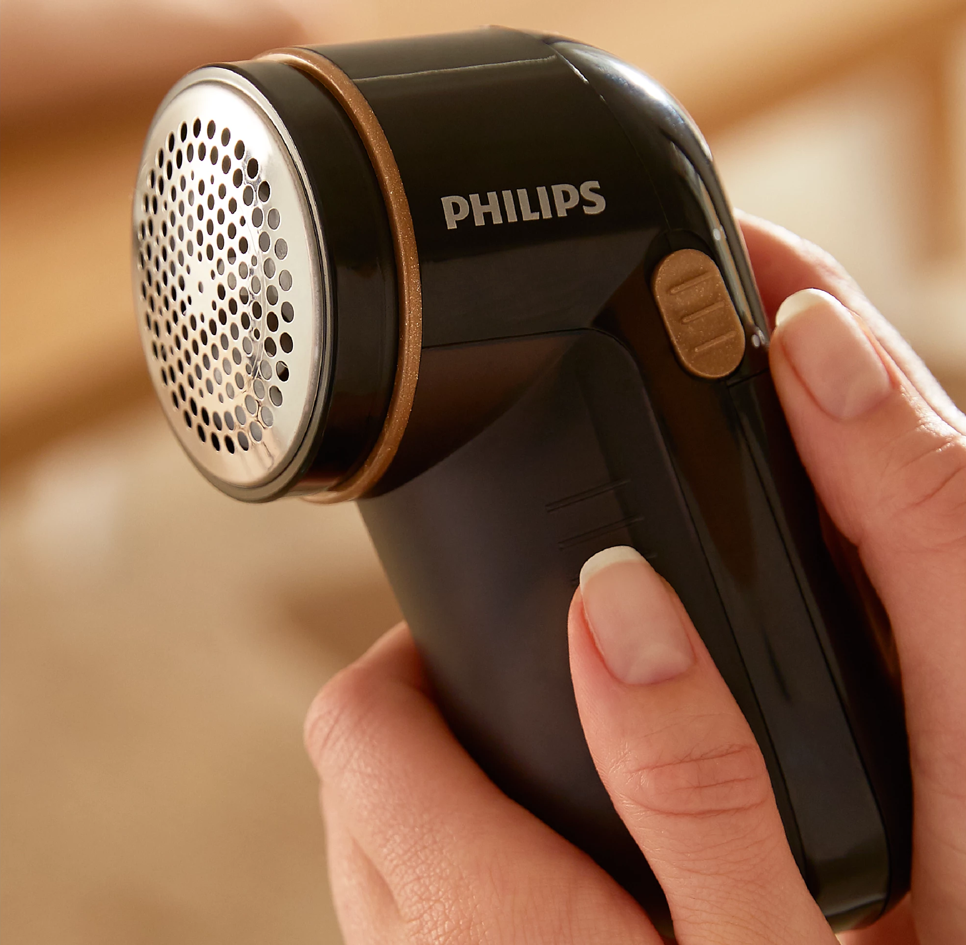 Eine Frau hält einen schwarzen Philips Stoffrasierer.