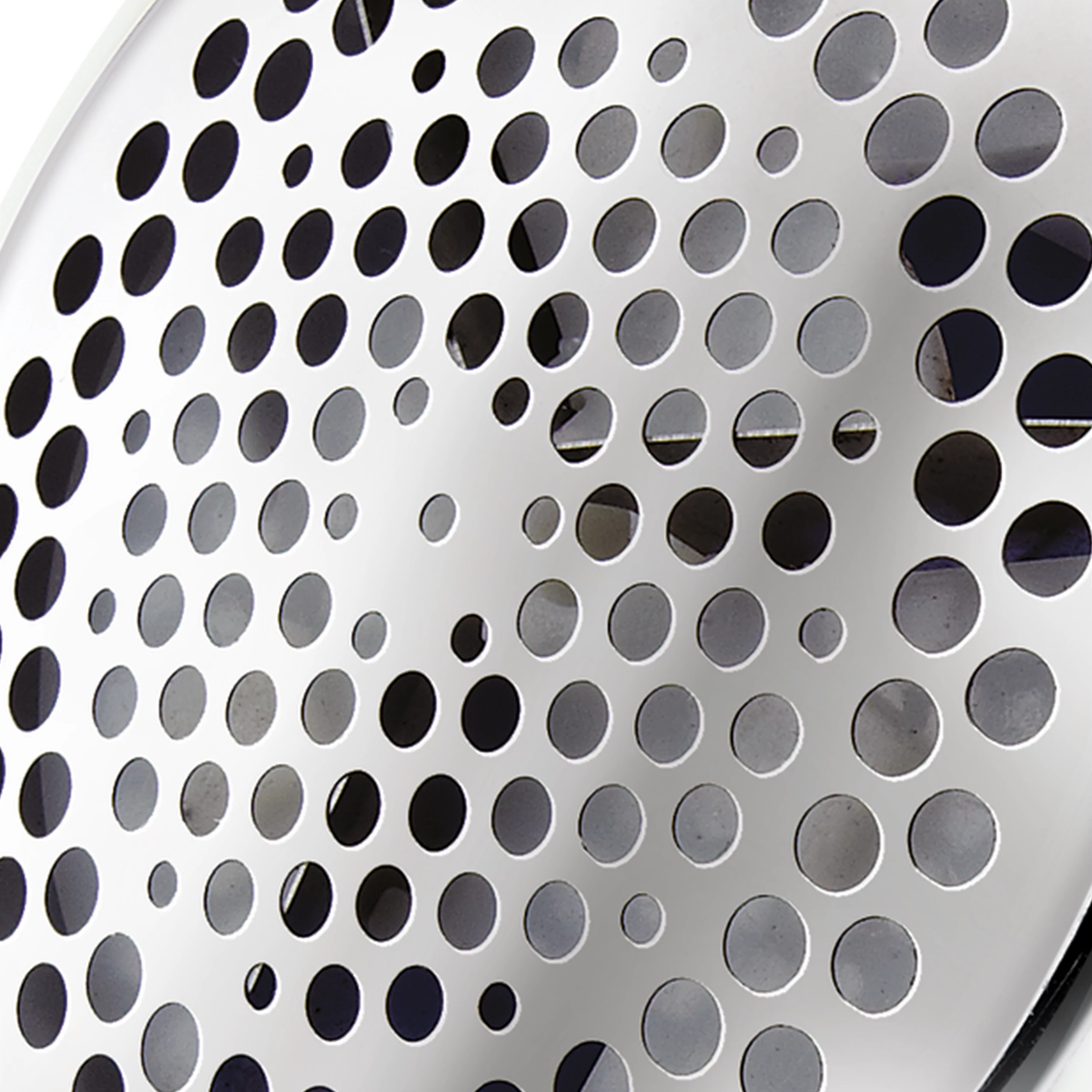 Nahaufnahme eines Metallgrills mit vielen kleinen Löchern, in Silber, nach rechts abgewinkelt.