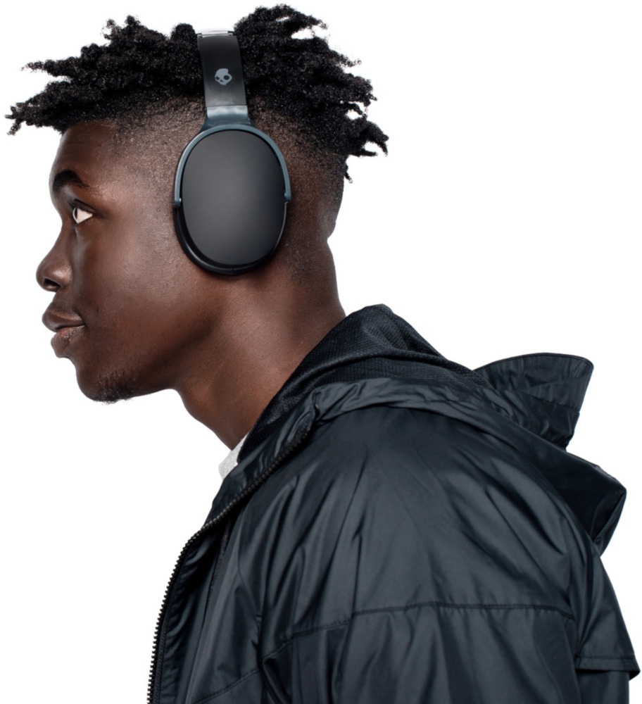 Jeune homme portant un casque noir. Vue de profil. Veste noire, fond blanc. Expression concentrée.