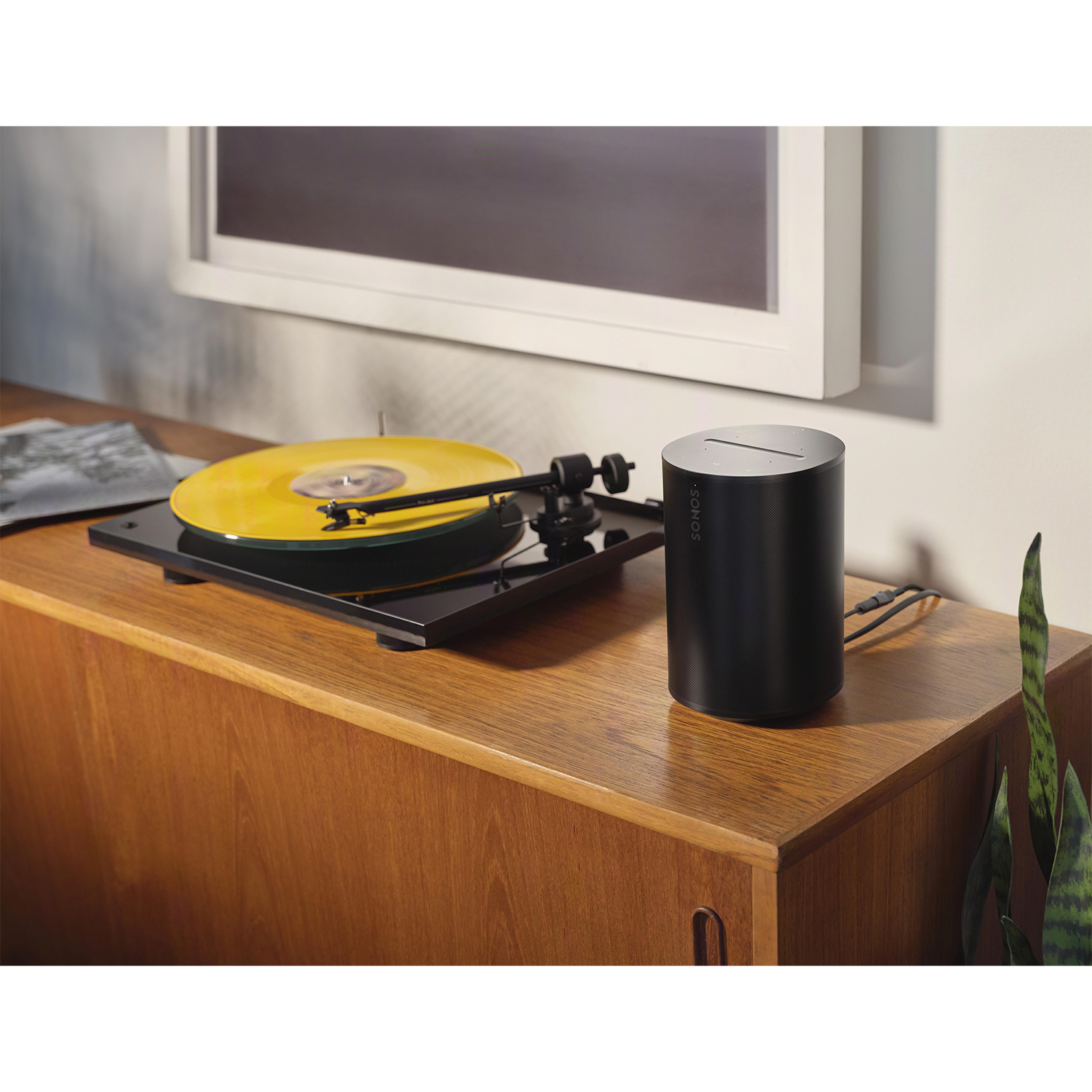 Un giradischi con un disco giallo in riproduzione. Altoparlante nero accanto.