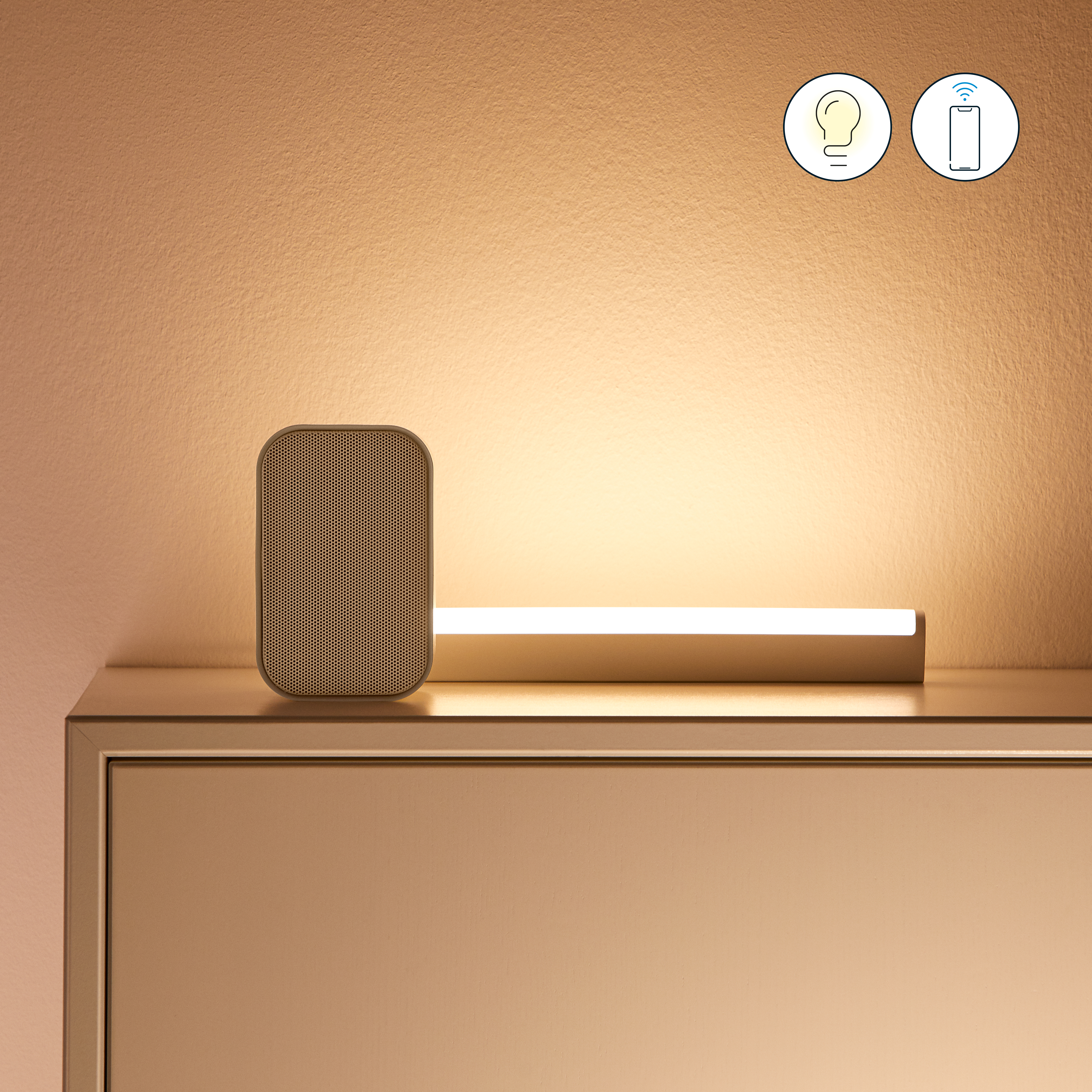 Un altavoz beige y una tira de luz sobre una cómoda. La luz está encendida y hay iconos para una bombilla y un mando a distancia.