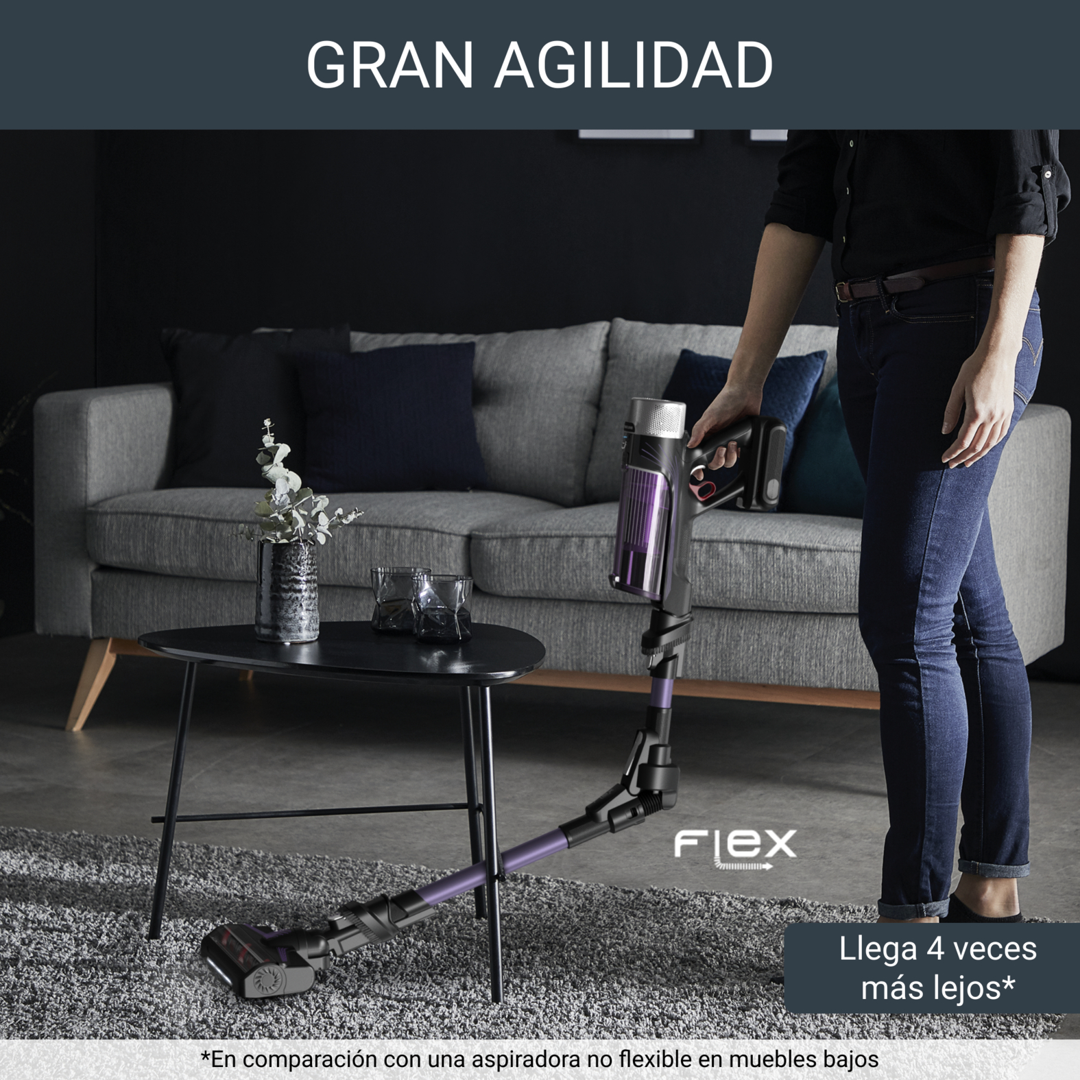 Persona aspirando con una aspiradora de mano en una sala de estar, cerca de un sofá.