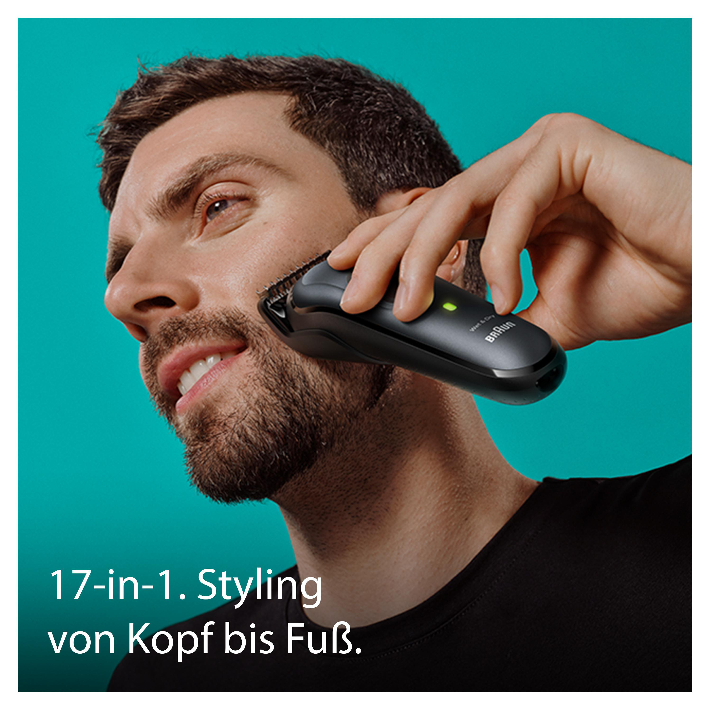 Ein Mann rasiert sein Gesicht mit einem schwarzen Trimmer. Er schaut in die Kamera.