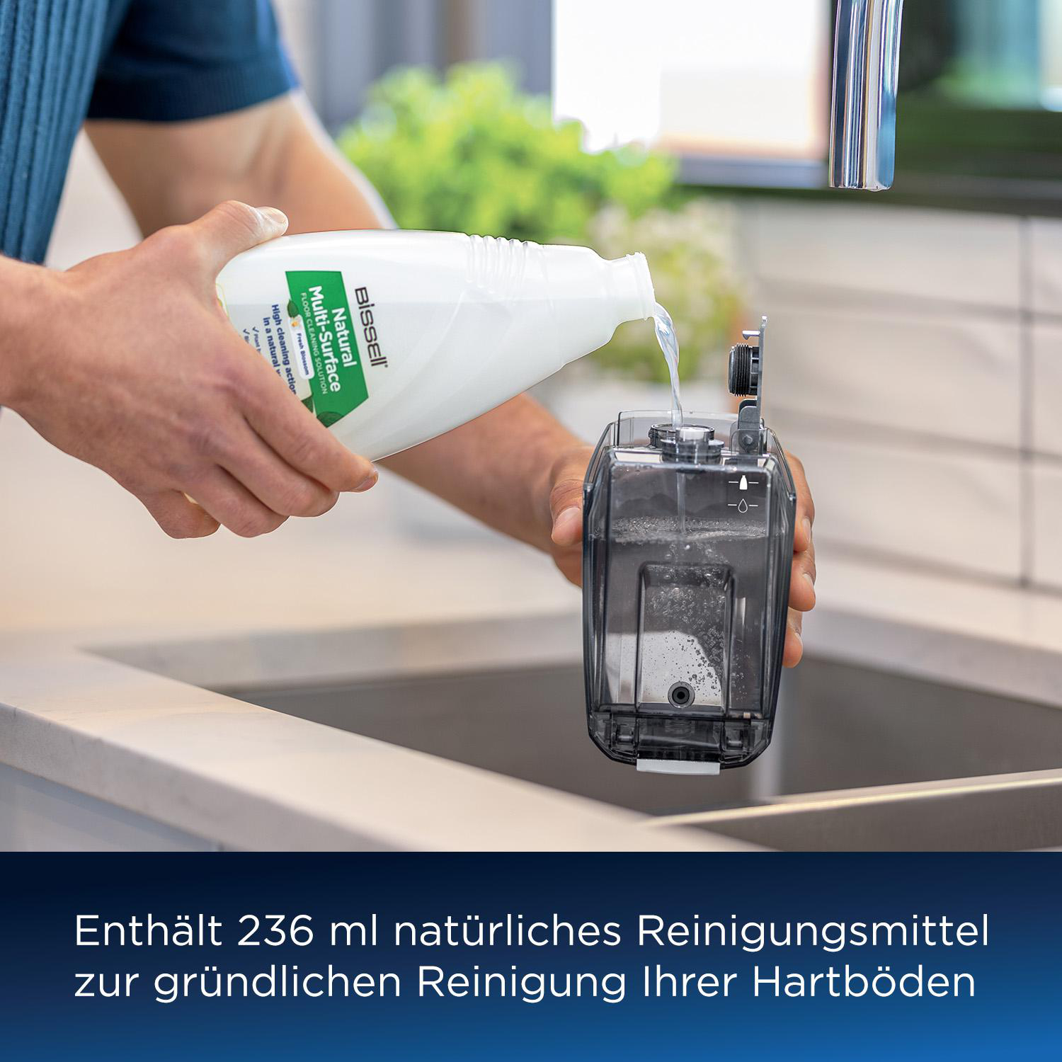 Eine Person gießt Reinigungslösung aus einer Flasche in ein Reinigungsgerät über einem Waschbecken.