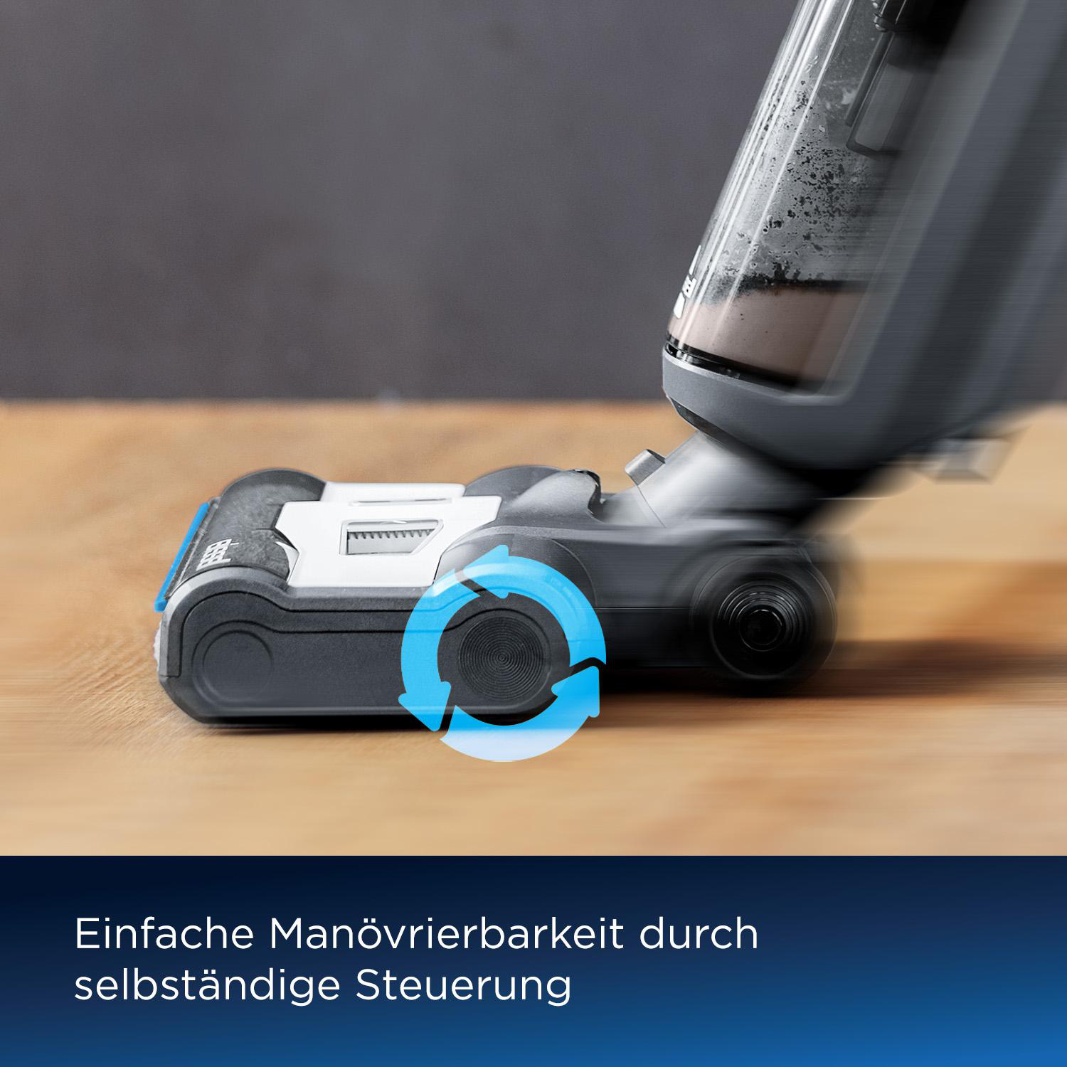 Nahaufnahme eines Staubsaugerkopfes mit blauem Pfeil, der Manövrierfähigkeit anzeigt. Hintergrund ist Holz und graue Wand.