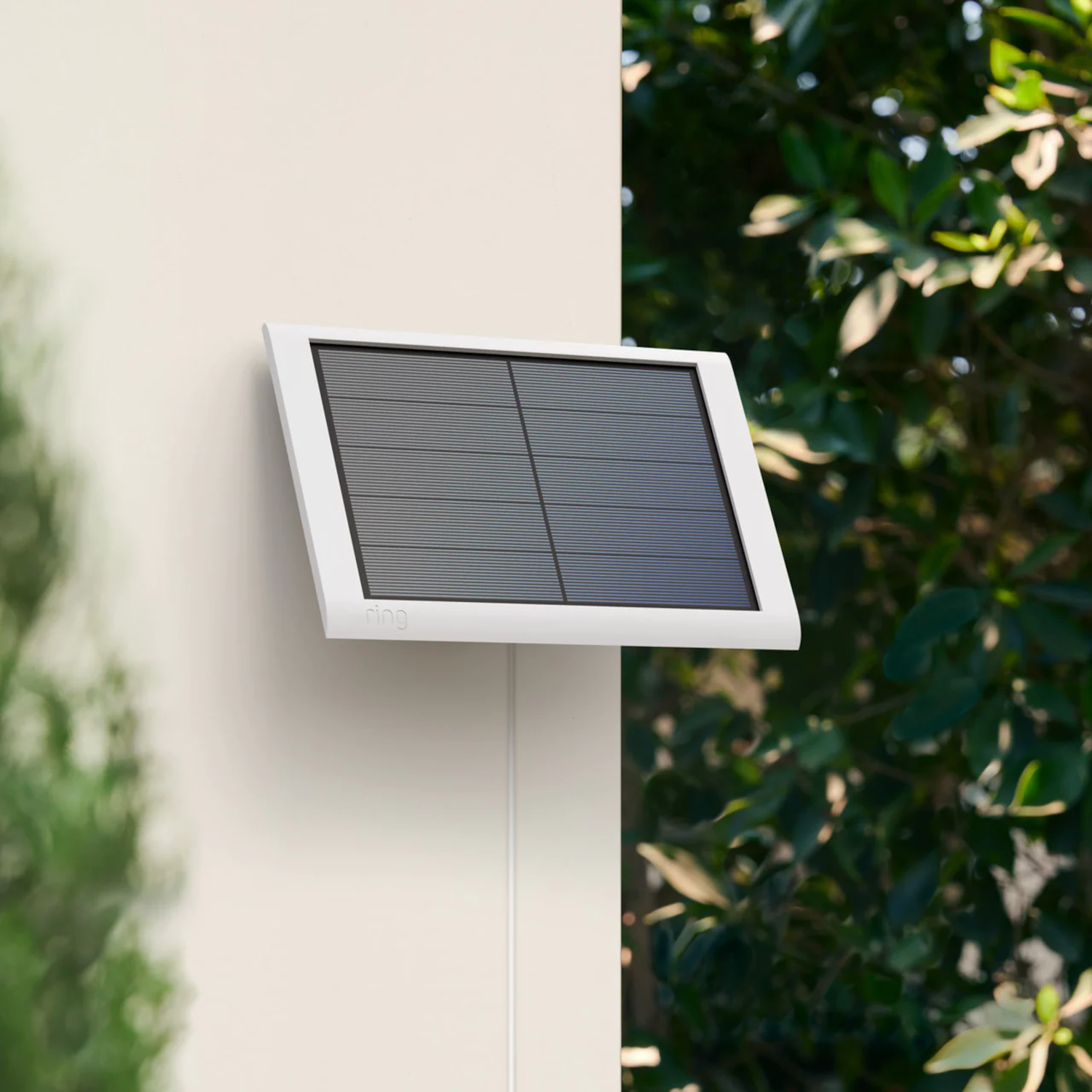 Un panneau solaire blanc monté sur un mur blanc, avec de la verdure en arrière-plan.