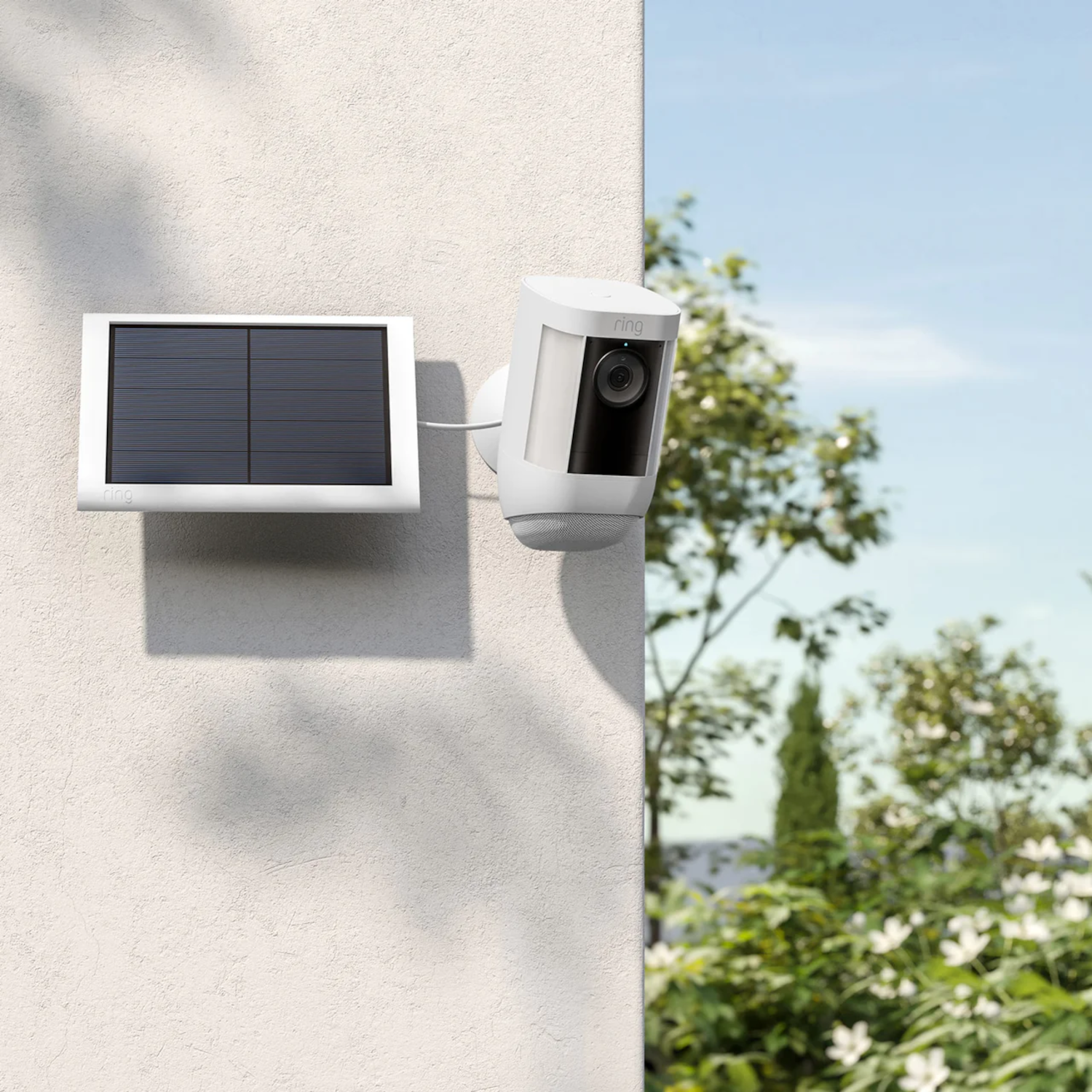 Une caméra de sécurité Ring blanche et un panneau solaire montés sur un mur.
