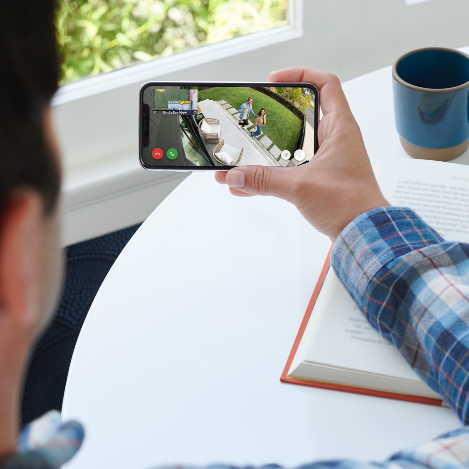 Personne tenant un téléphone affichant la vue d'une caméra de sécurité.