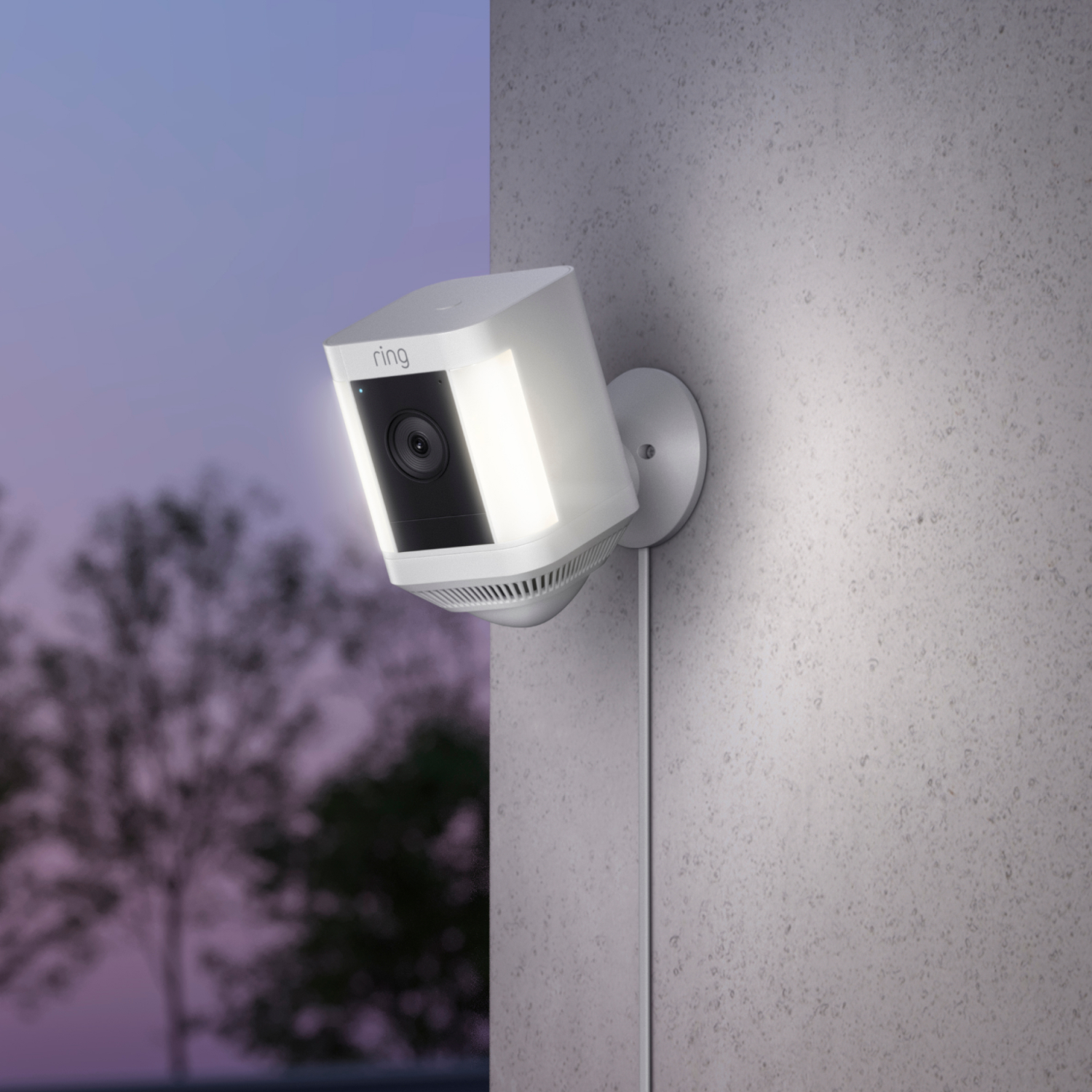 Caméra de sécurité Ring blanche sur un mur, avec lumière et câble, prise de jour.