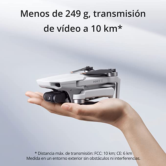 Un pequeño dron blanco sostenido por una mano, con texto en español, fondo negro.