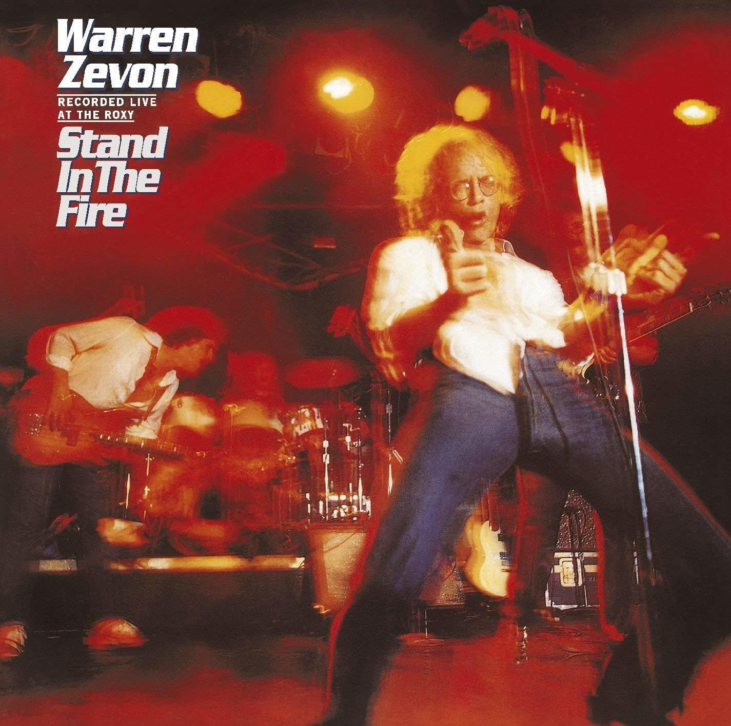 Album borító. Warren Zevon a színpadon, basszusgitározik, piros fényben. Cím: Stand in the Fire.