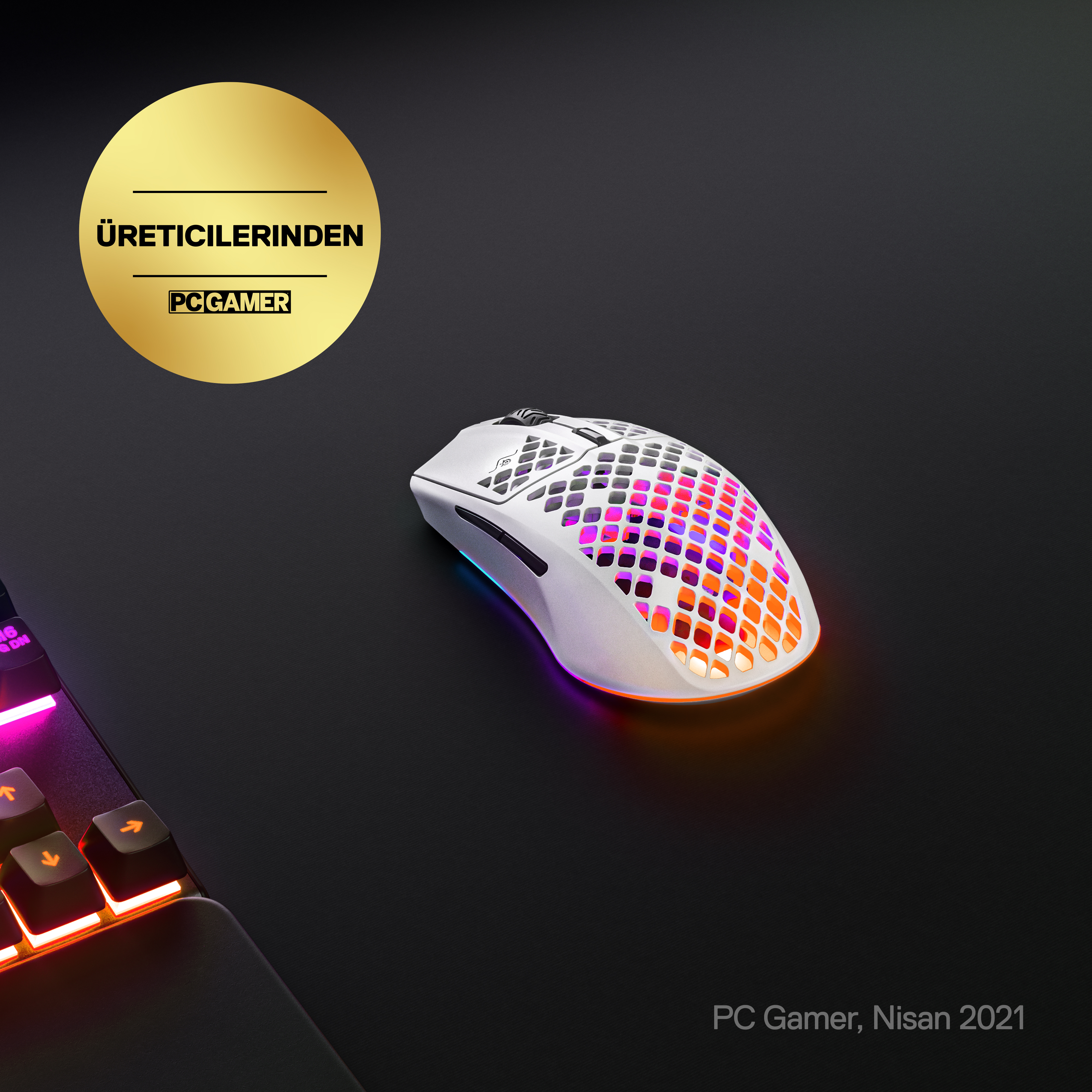 Siyah zeminde RGB aydınlatmalı beyaz oyuncu faresi. Altın PC Gamer logosu.
