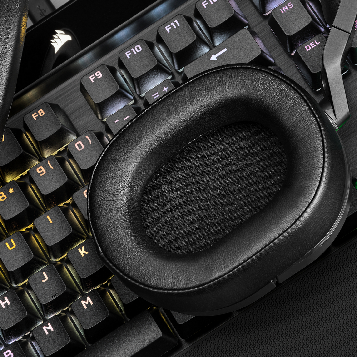 Een zwart oorkussen van een headset dat op een zwart toetsenbord ligt met geel verlichte toetsen.