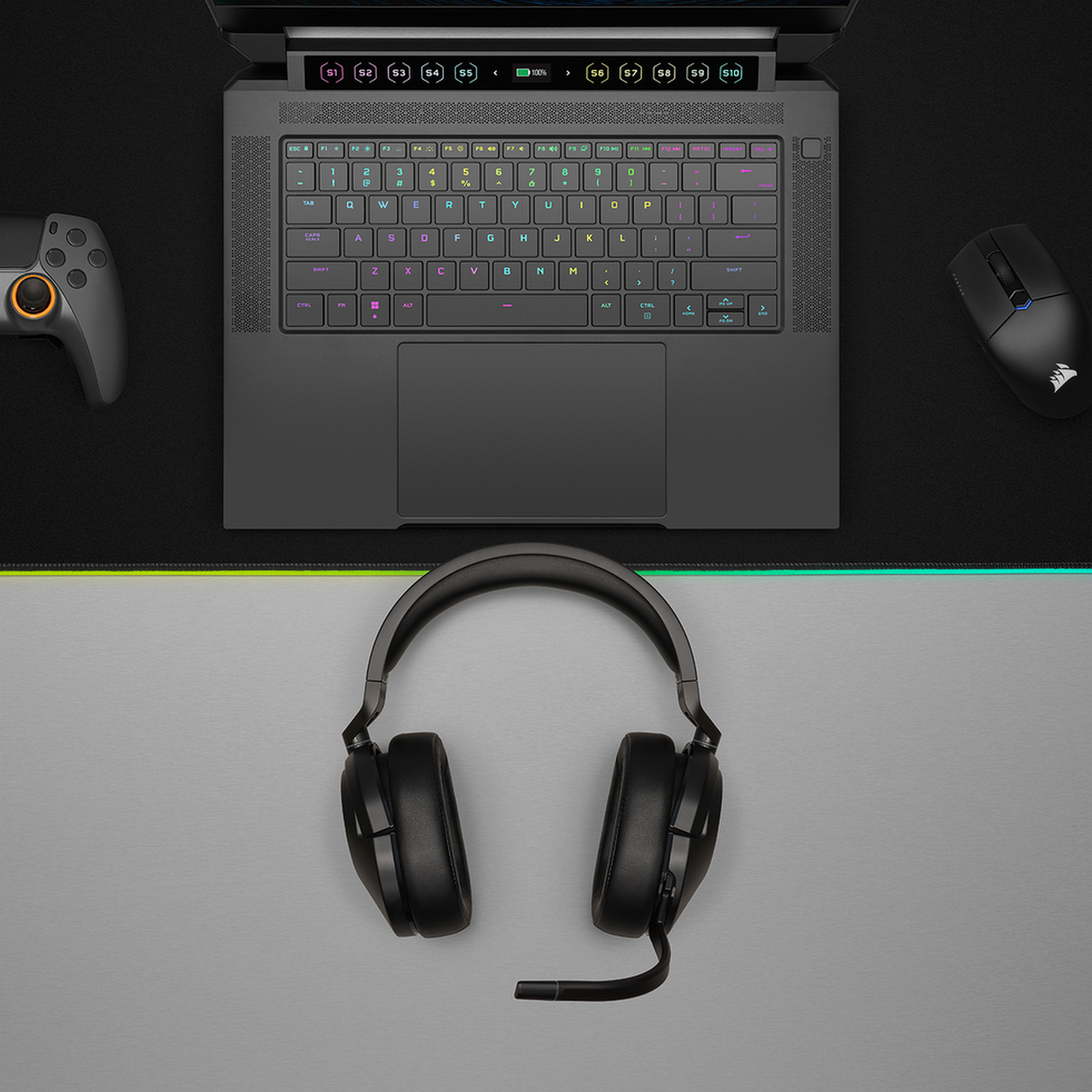 Gaming setup met een laptop, muis, hoofdtelefoon en gamepad op een zwart oppervlak.