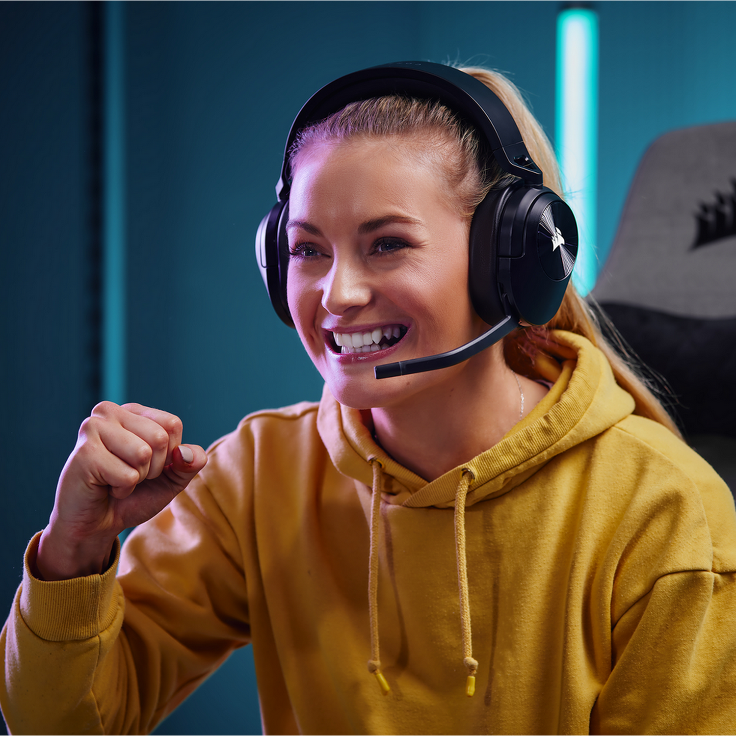 Een vrouw met een gamingheadset glimlacht en juicht.