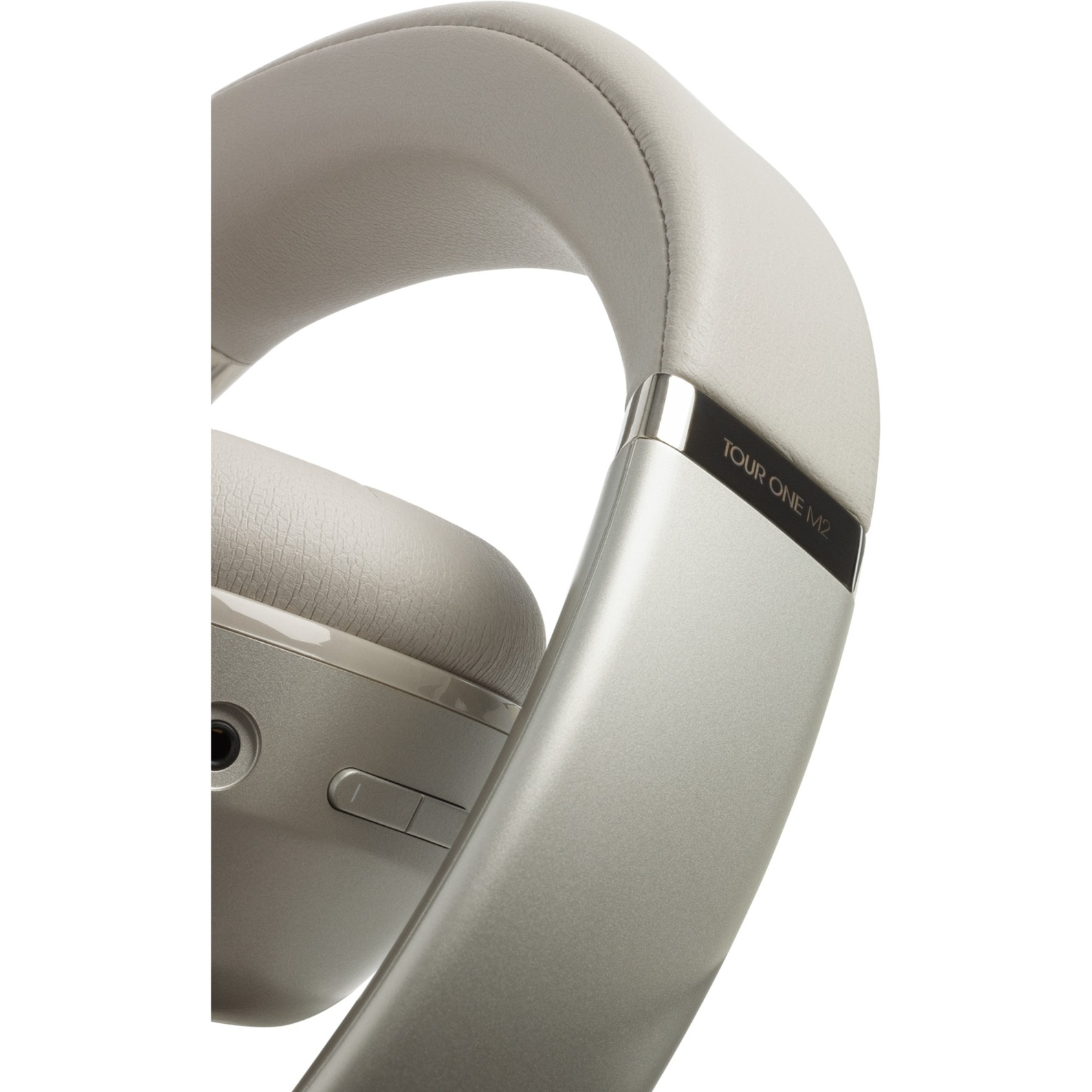 Primer plano de un auricular plateado. El texto 'TOUR ONE M2' es visible.