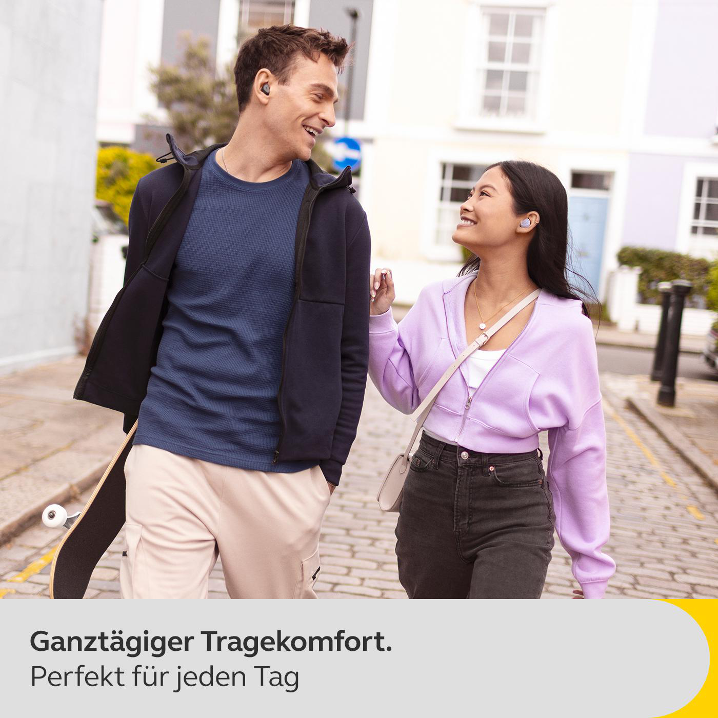 Paar spaziert mit Ohrhörern auf der Straße. Text: Bequem für jeden Tag zu tragen.