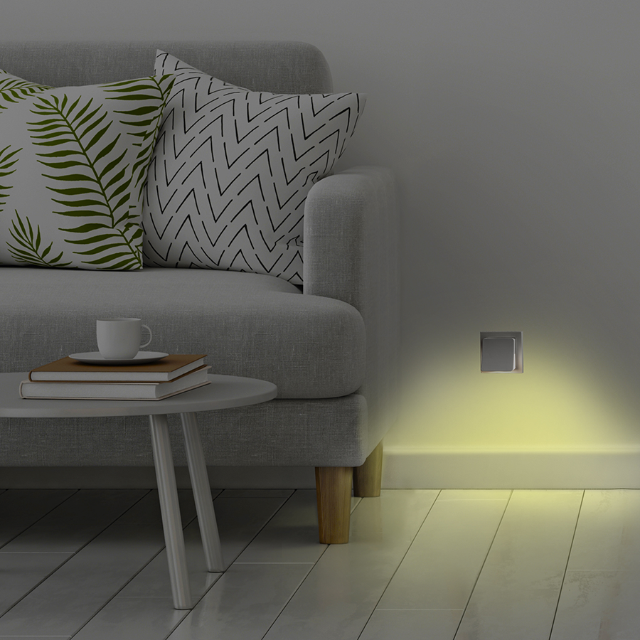 Interior scene with a gray sofa, side table, and a wall-mounted light emitting yellow light.
