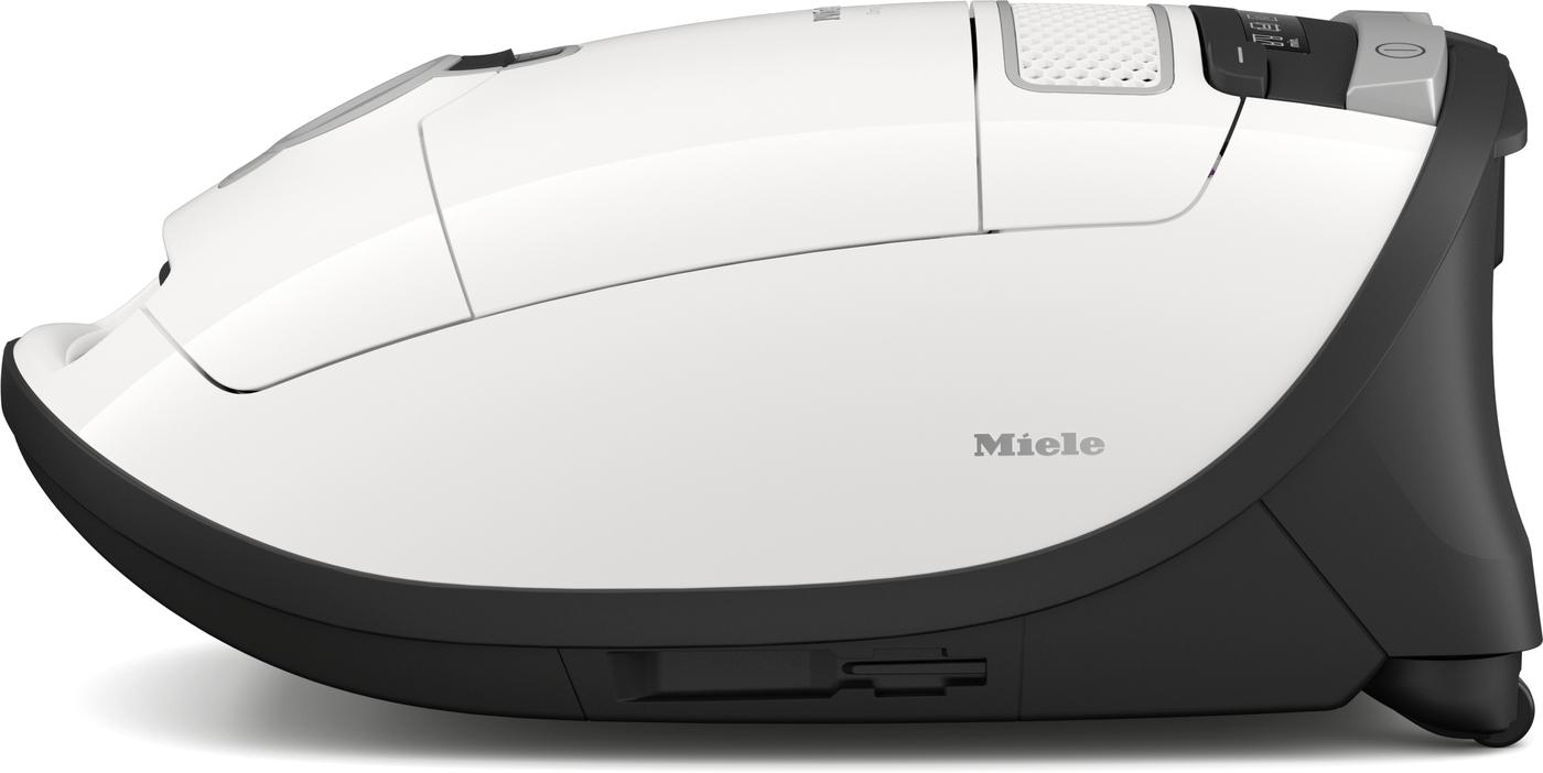 Ein weißer Miele Staubsauger, Seitenansicht, auf weißer Oberfläche. Schwarze Akzente und Miele-Logo sichtbar.