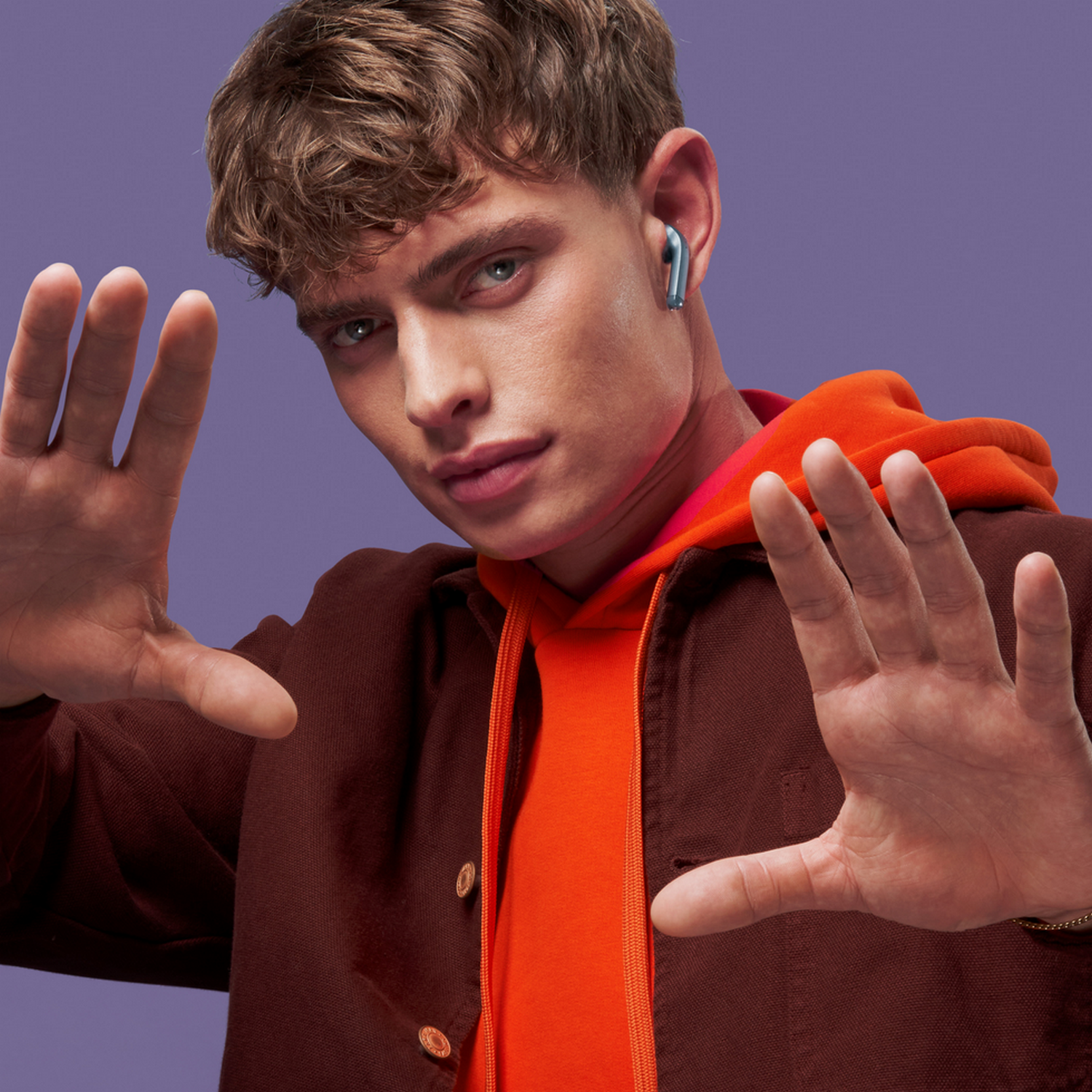 Man with earbuds in ear. Purple background.
