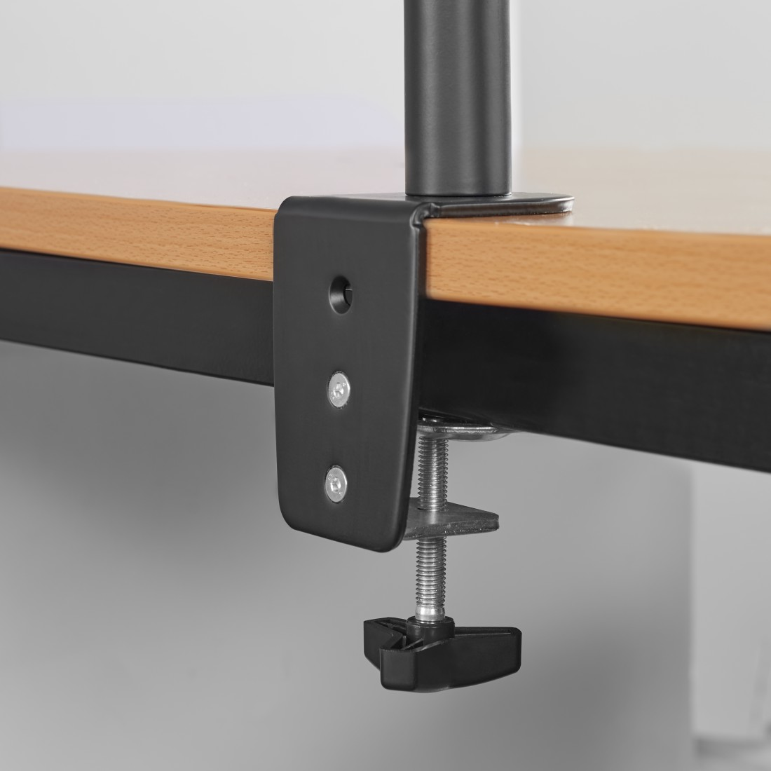 Soporte negro montado sobre una superficie de madera. Un tornillo lo sujeta en su lugar.