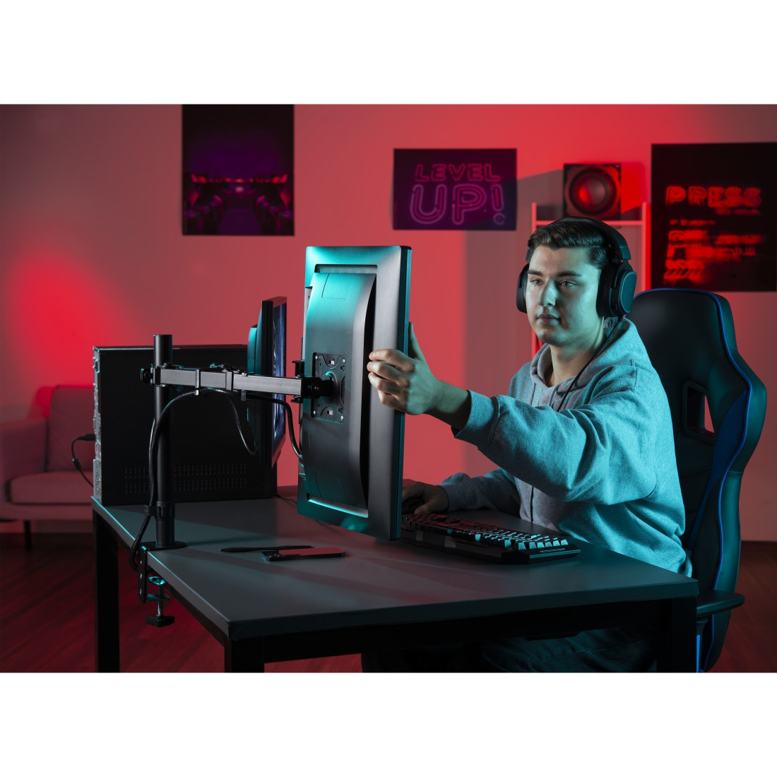 Un hombre con auriculares ajustando un monitor. Está en una configuración de juego.