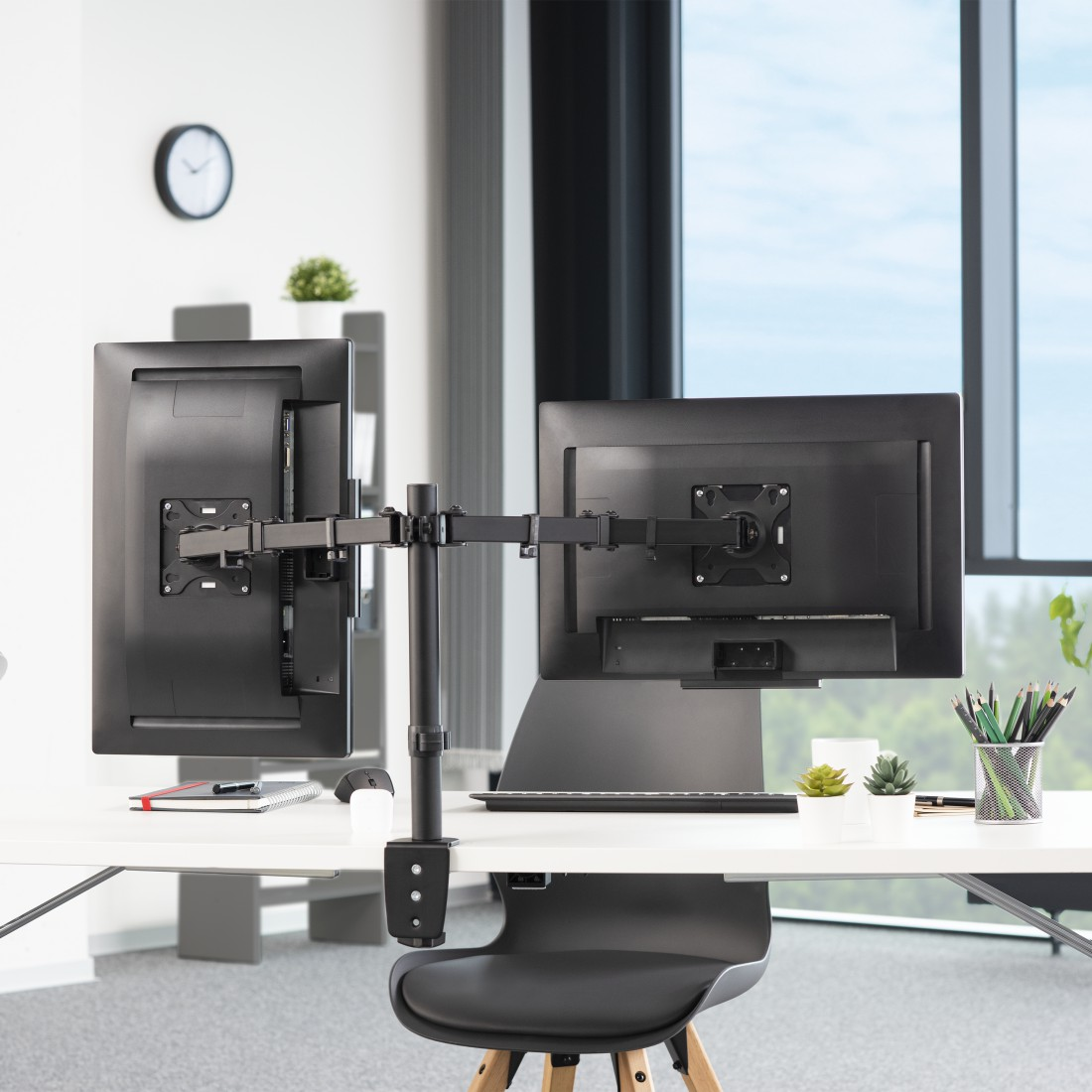 Dos monitores de computadora negros montados en un soporte, colocados en un escritorio blanco.