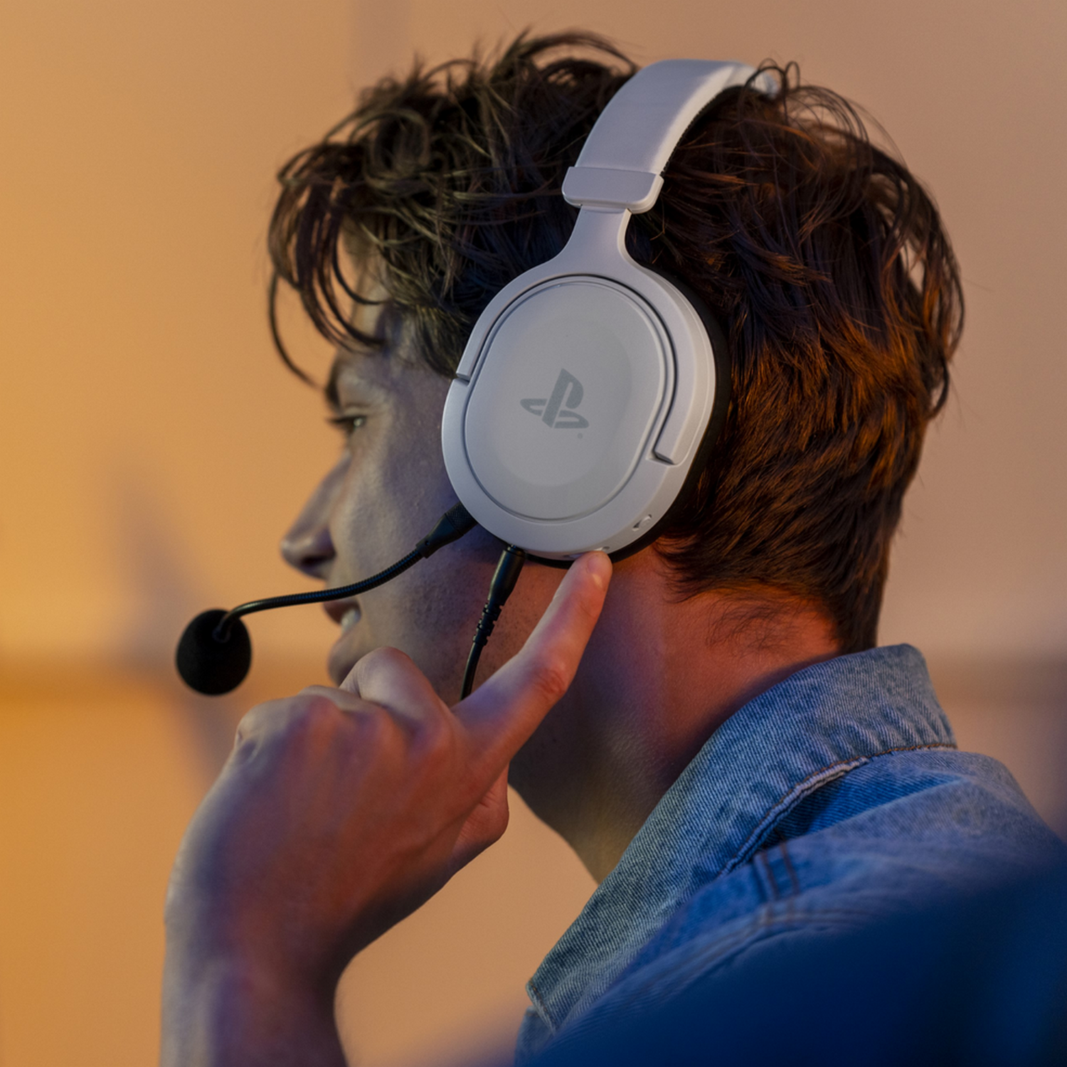 Persoon met witte koptelefoon en microfoon, die zijn oor aanraakt.