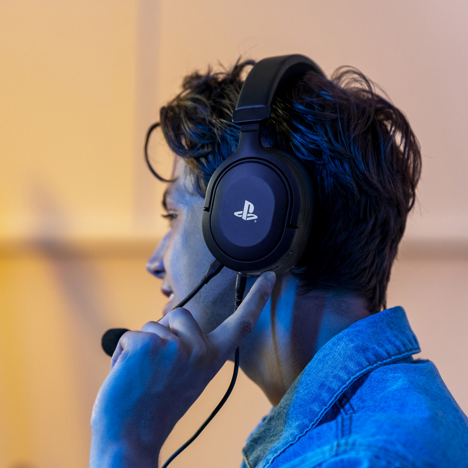 Man met zwarte headset, wijst naar microfoon, wazige achtergrond.