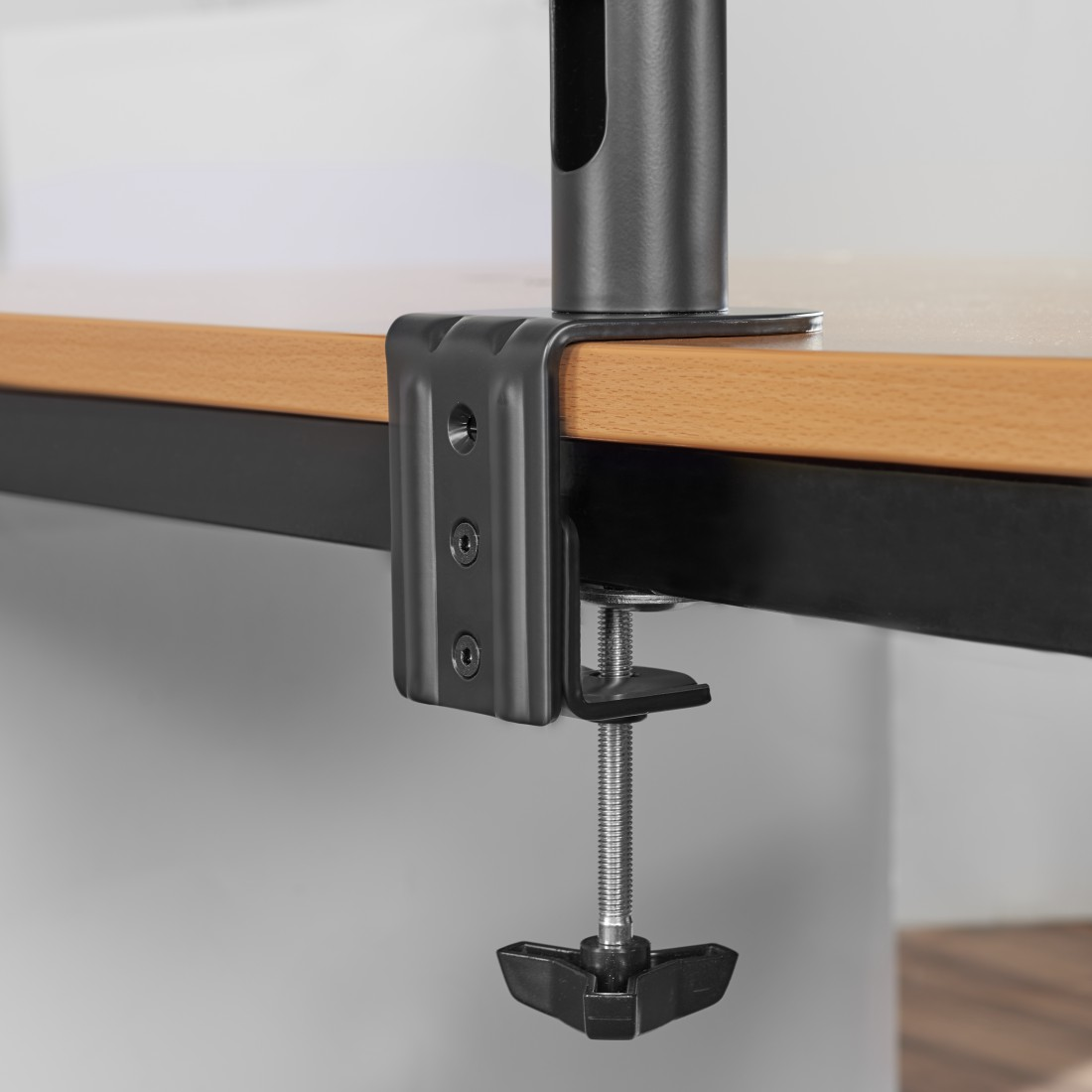 Primer plano de una abrazadera negra en el borde de una mesa de madera, con perilla negra.