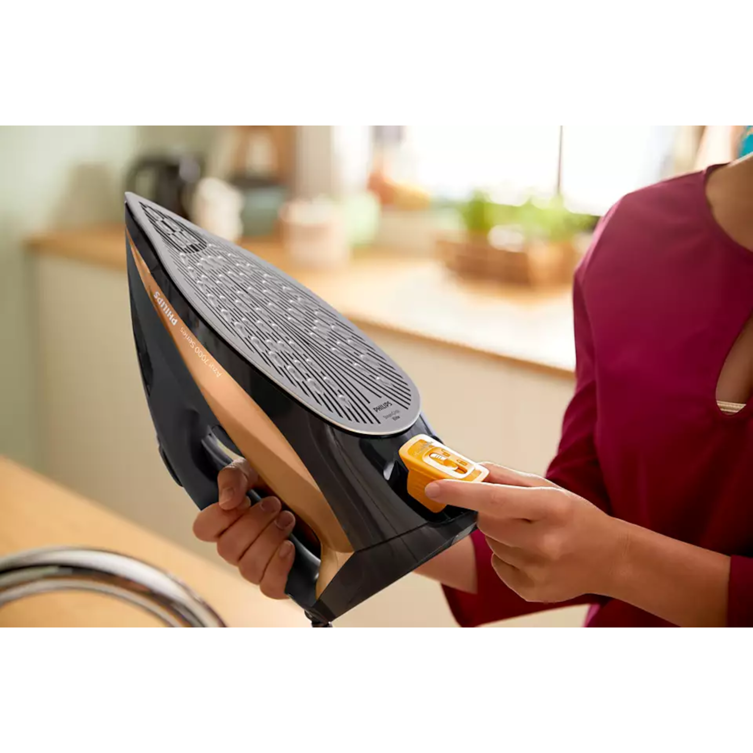 A black and gold iron being held by a person.