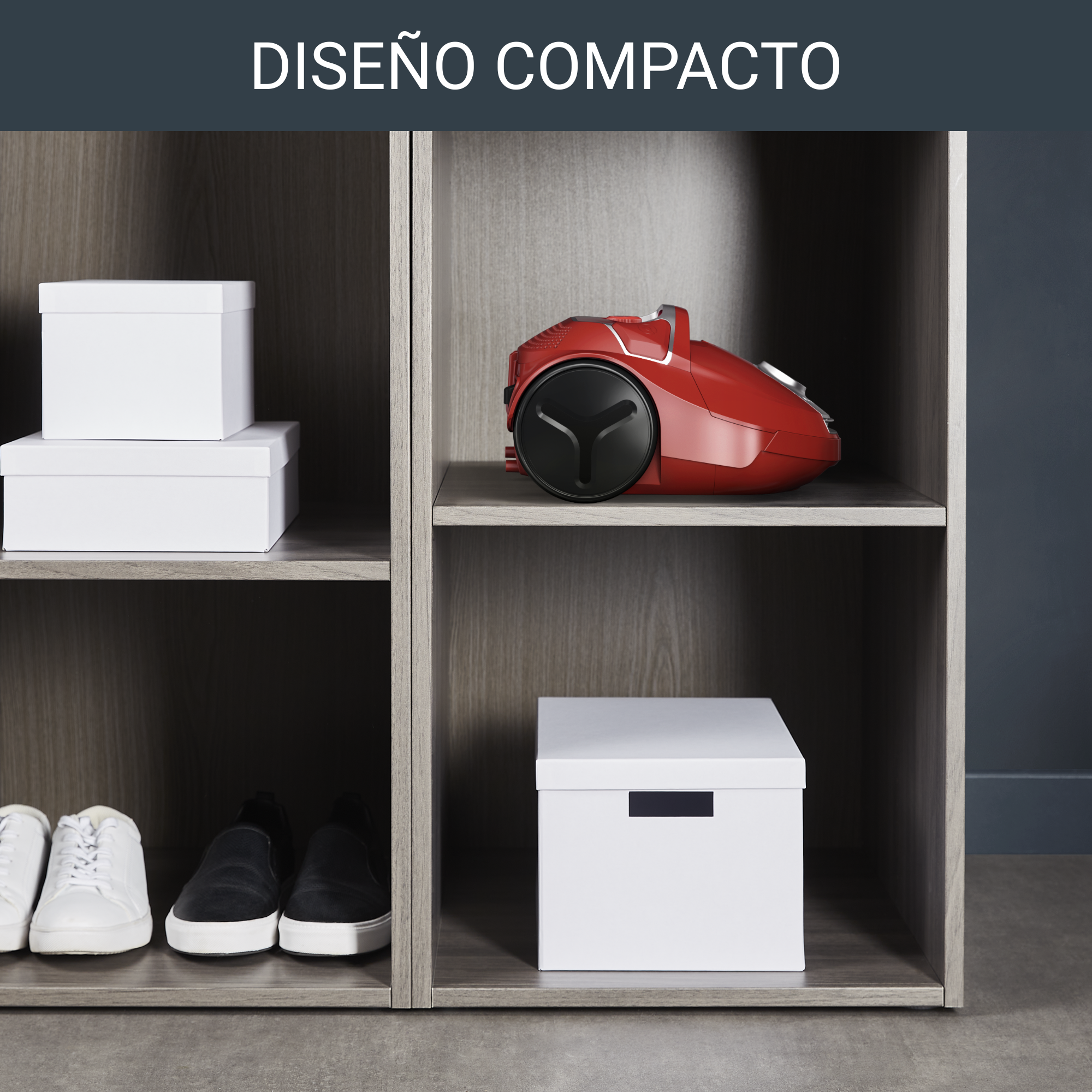 Una aspiradora roja en un armario gris con cajas blancas y zapatos.