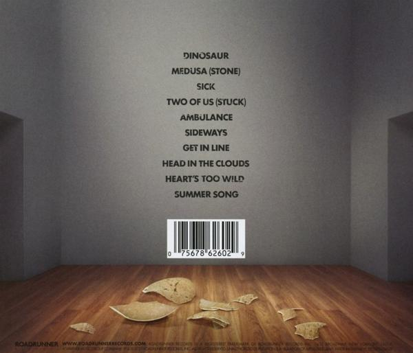 Rückseite eines CD-Covers mit Texten an einer grauen Wand und zerbrochenen Tellern auf einem Holzboden. Ein Barcode ist sichtbar.