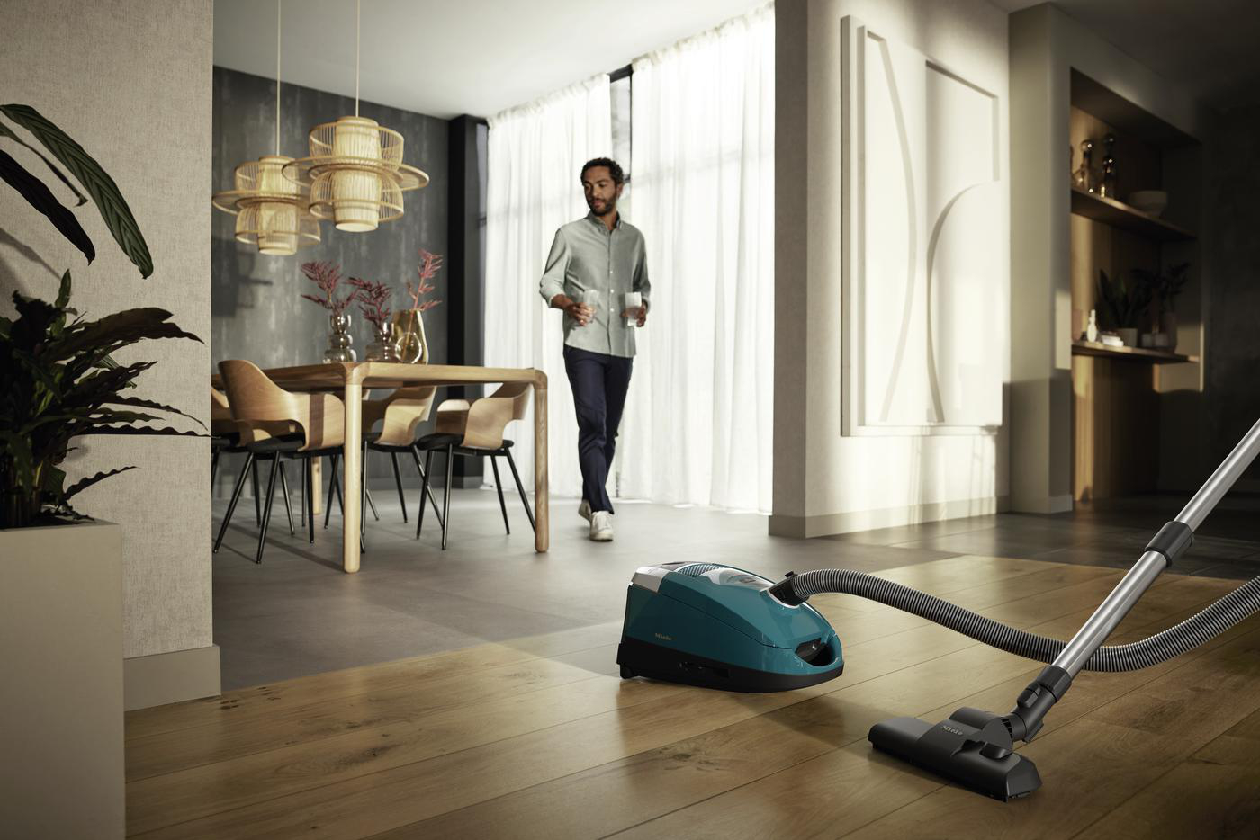 Ein Mann geht in einem modernen Zuhause mit einem Staubsauger.