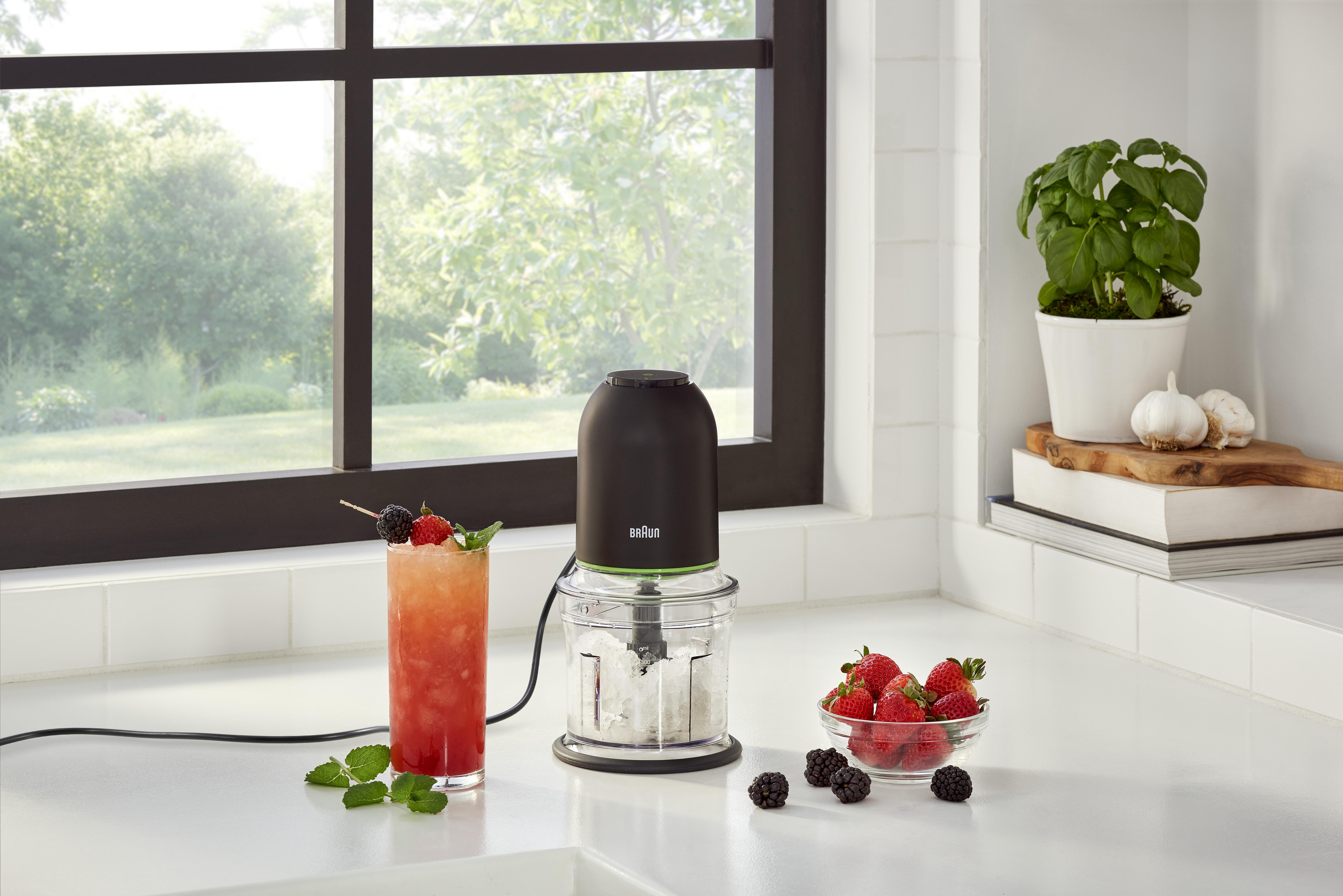Küchenszene mit Küchenmaschine, Cocktail, Beeren und Fenster im Hintergrund.