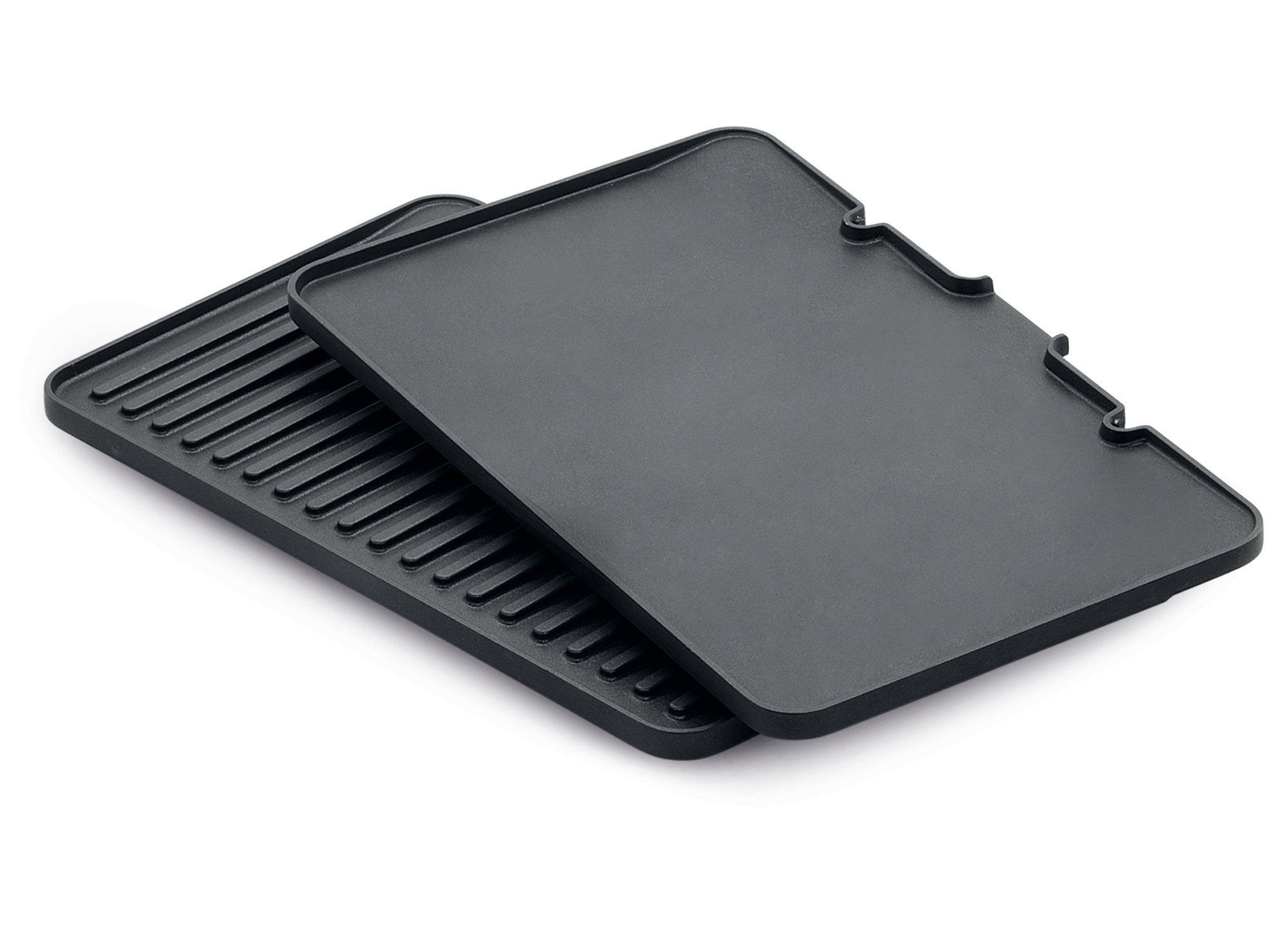 Zwei schwarze Grillplatten, eine mit Rippen und eine flache, auf weißem Hintergrund.