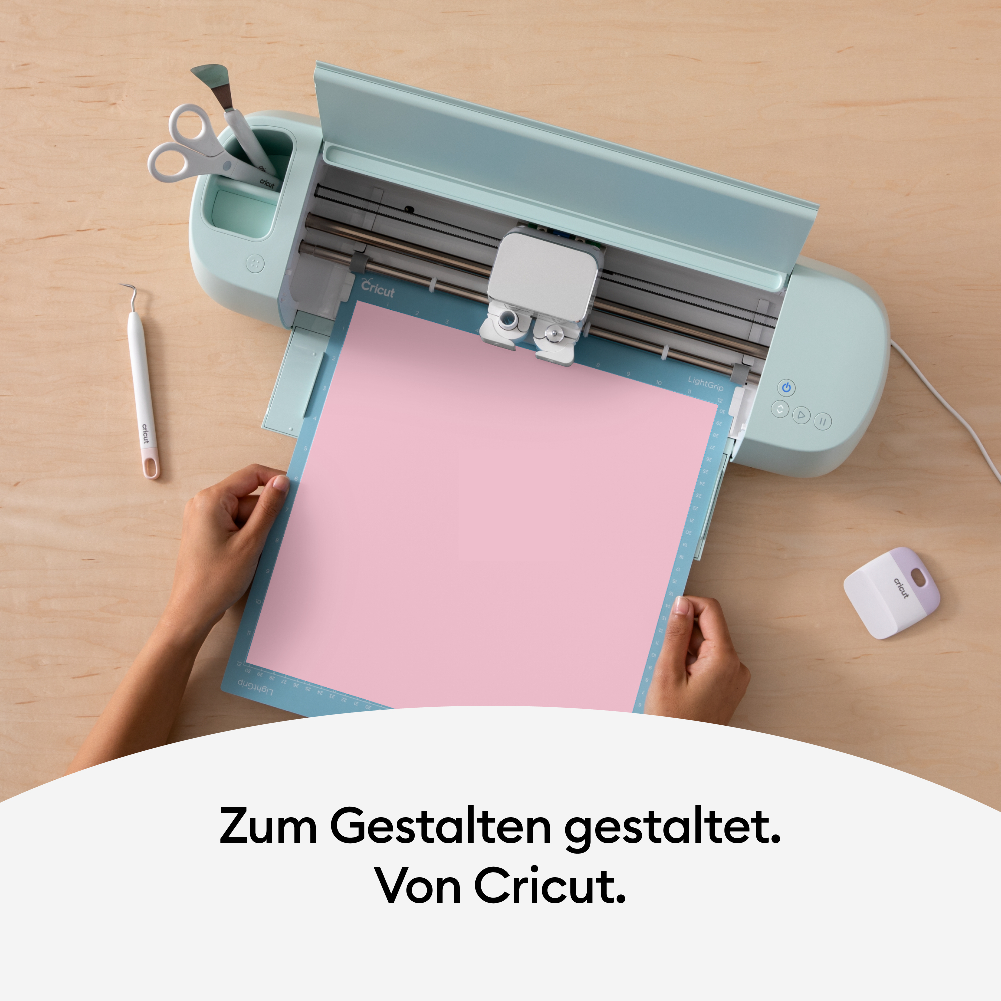 Person benutzt eine Cricut-Maschine, rosa Papier auf blauer Matte.