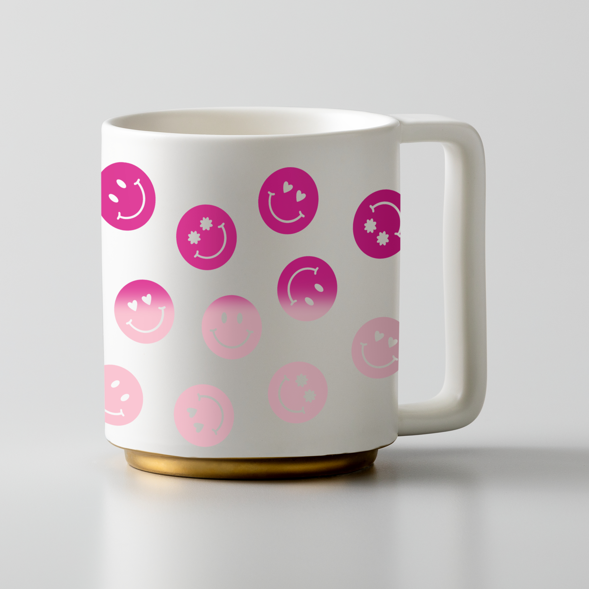 Weißer Becher mit pinken Smiley-Gesichtern und Herzen, goldener Boden, weißer Griff.