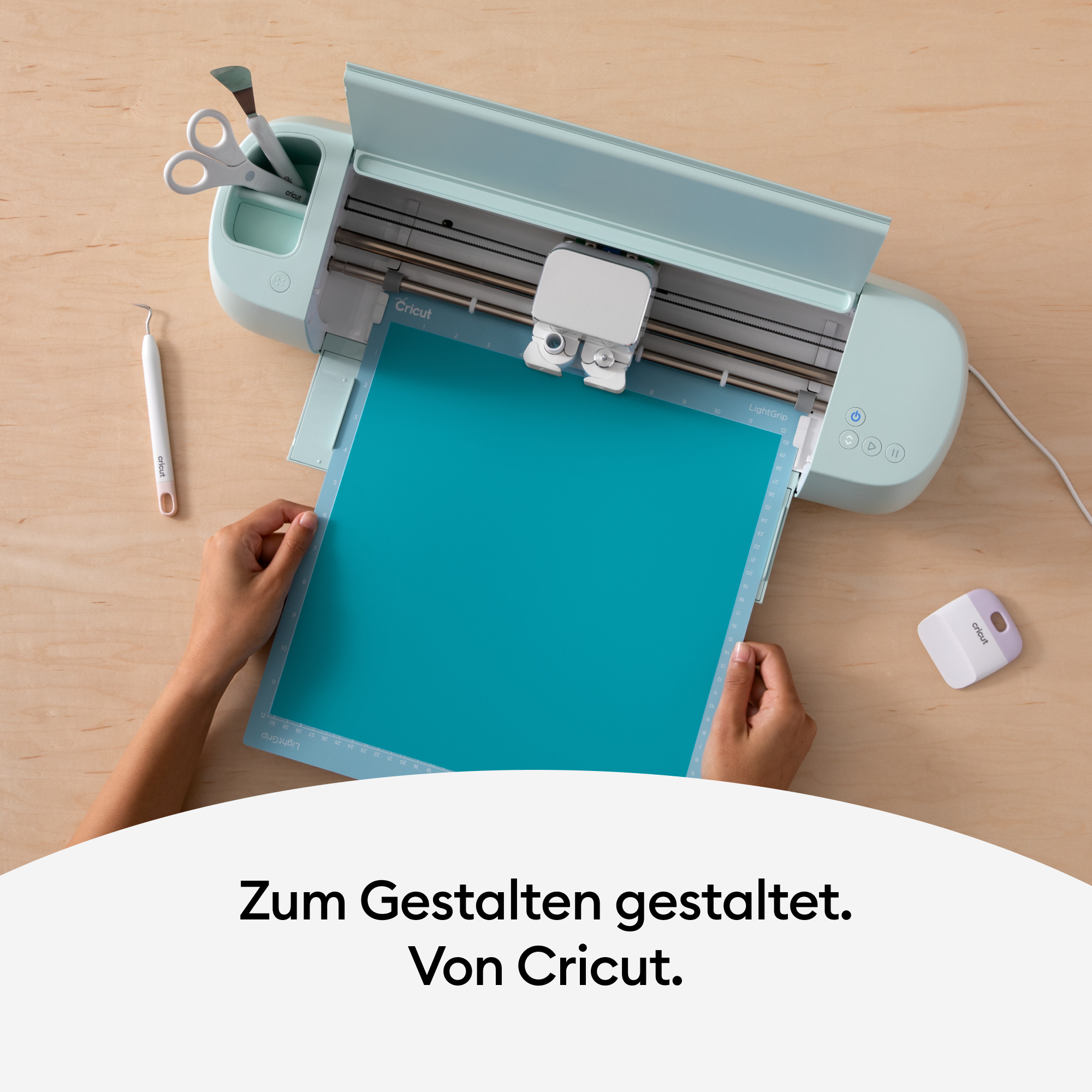Eine Cricut-Maschine mit türkisfarbenem Papier, das auf einer Holzoberfläche geschnitten wird.