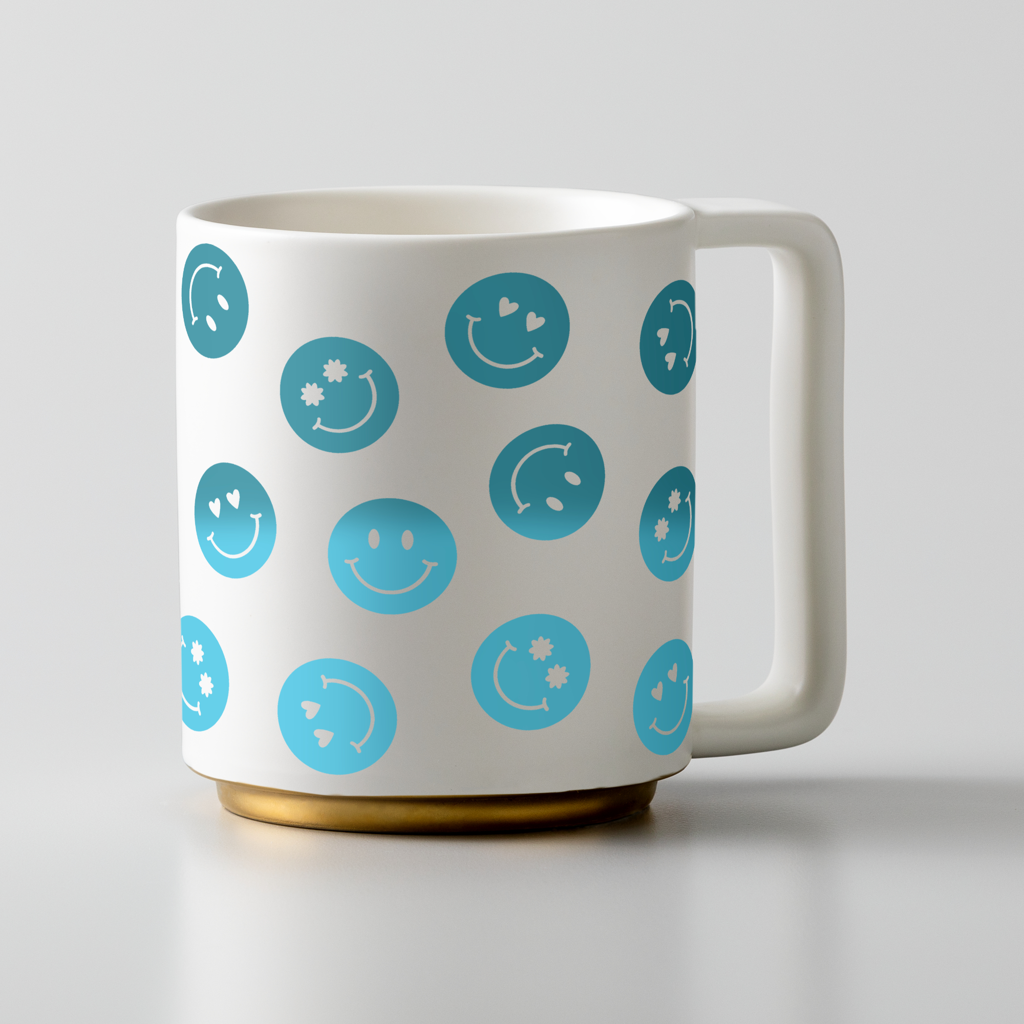 Weiße Tasse mit blauen Smiley-Mustern und goldenem Boden.