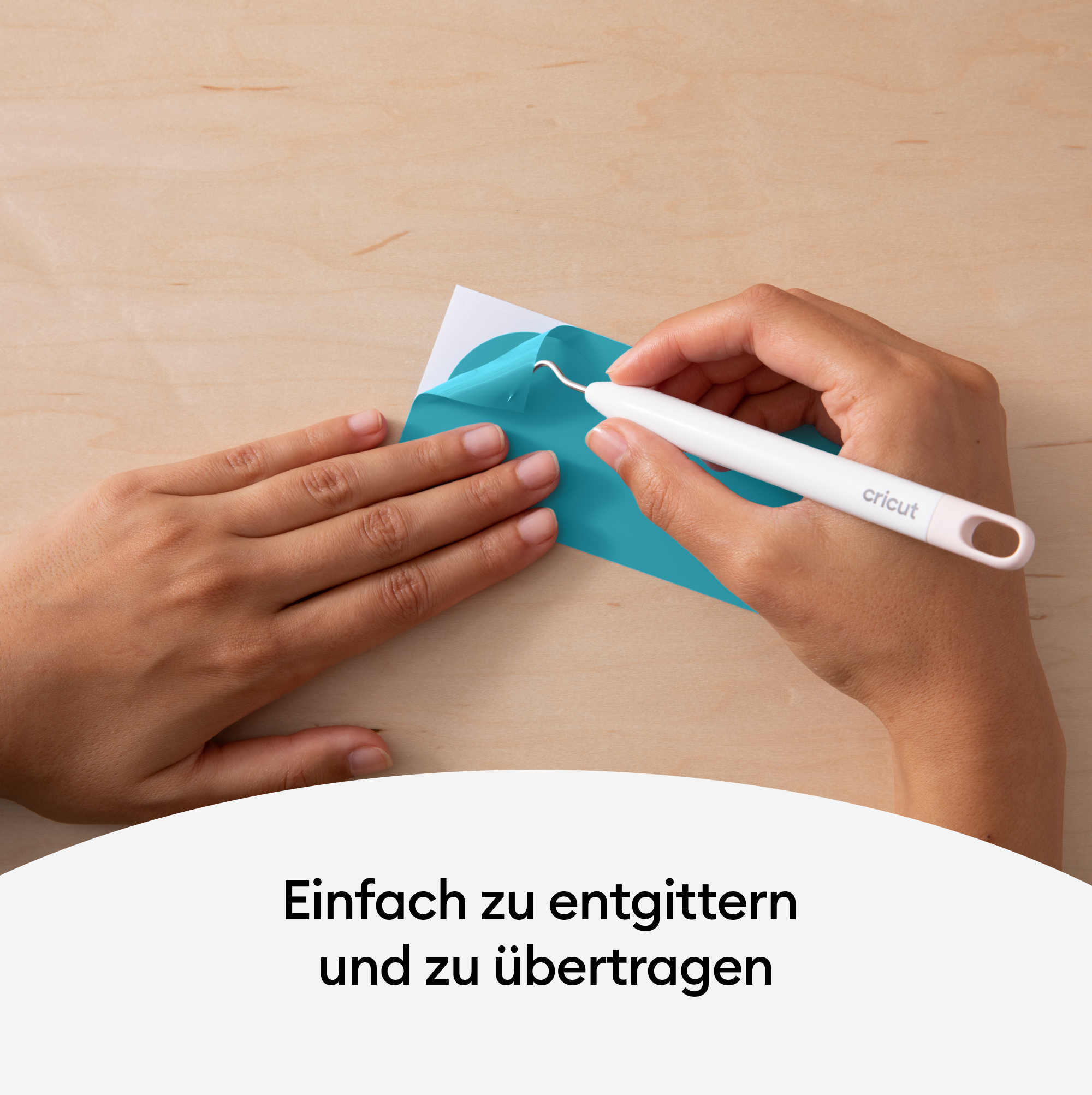 Hände verwenden ein Cricut-Entgitterwerkzeug, um blaues Vinyl von weißem Träger abzuziehen. Die Oberfläche ist Holzmaserung.