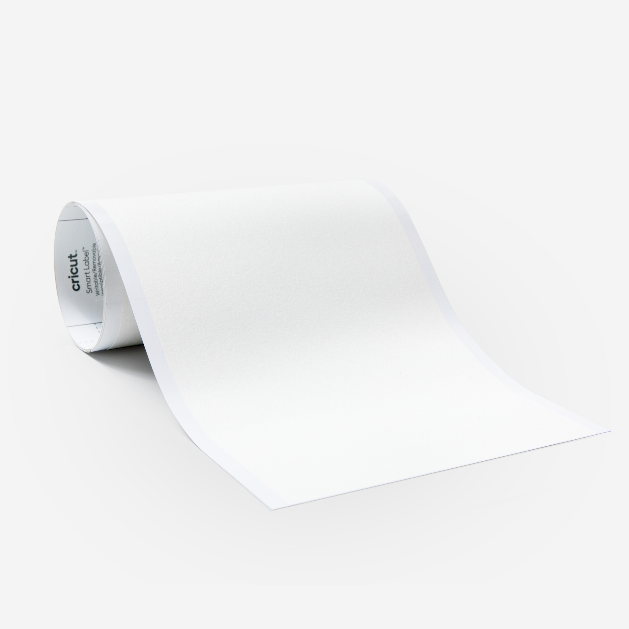 Eine Rolle weißes Cricut Smart Label-Papier, teilweise abgerollt vor weißem Hintergrund.